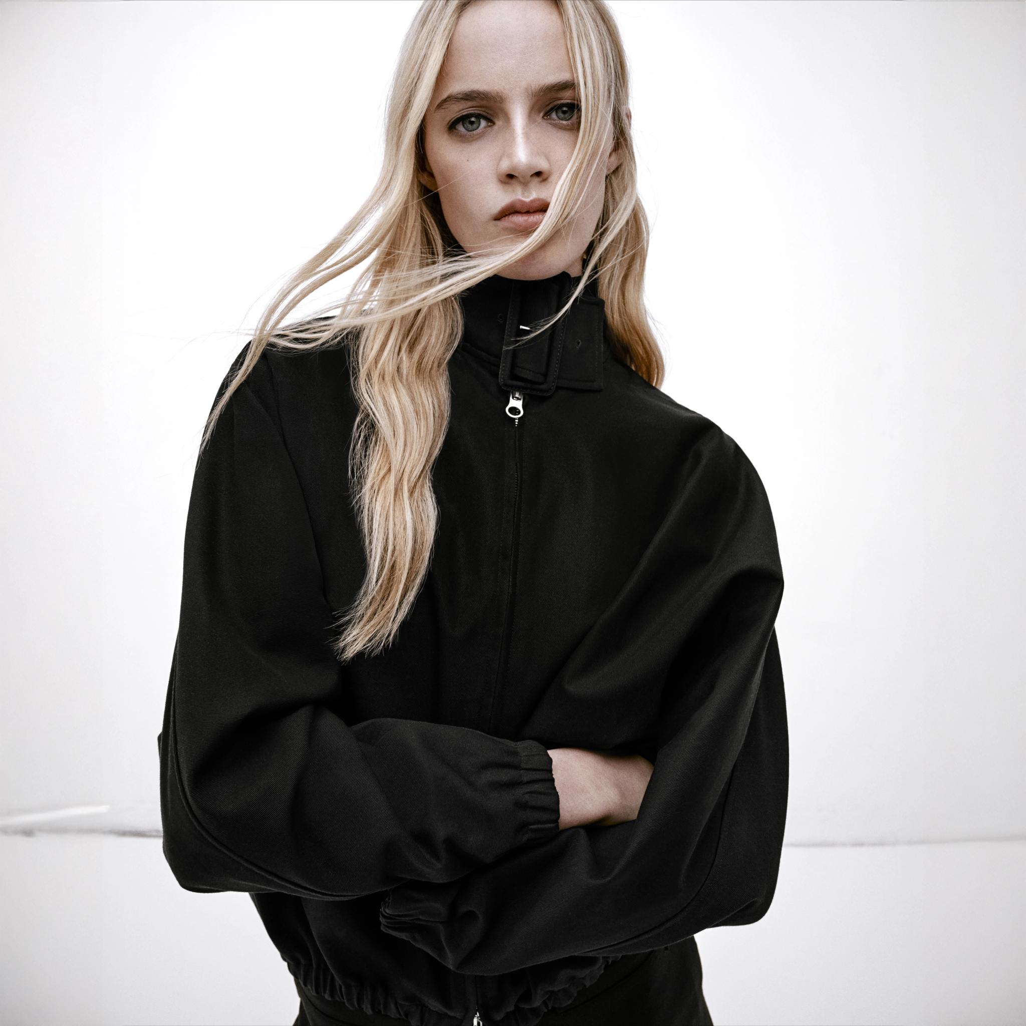 Veste noire élégante Courrèges avec col montant, portée par un modèle pour la mode en ligne.