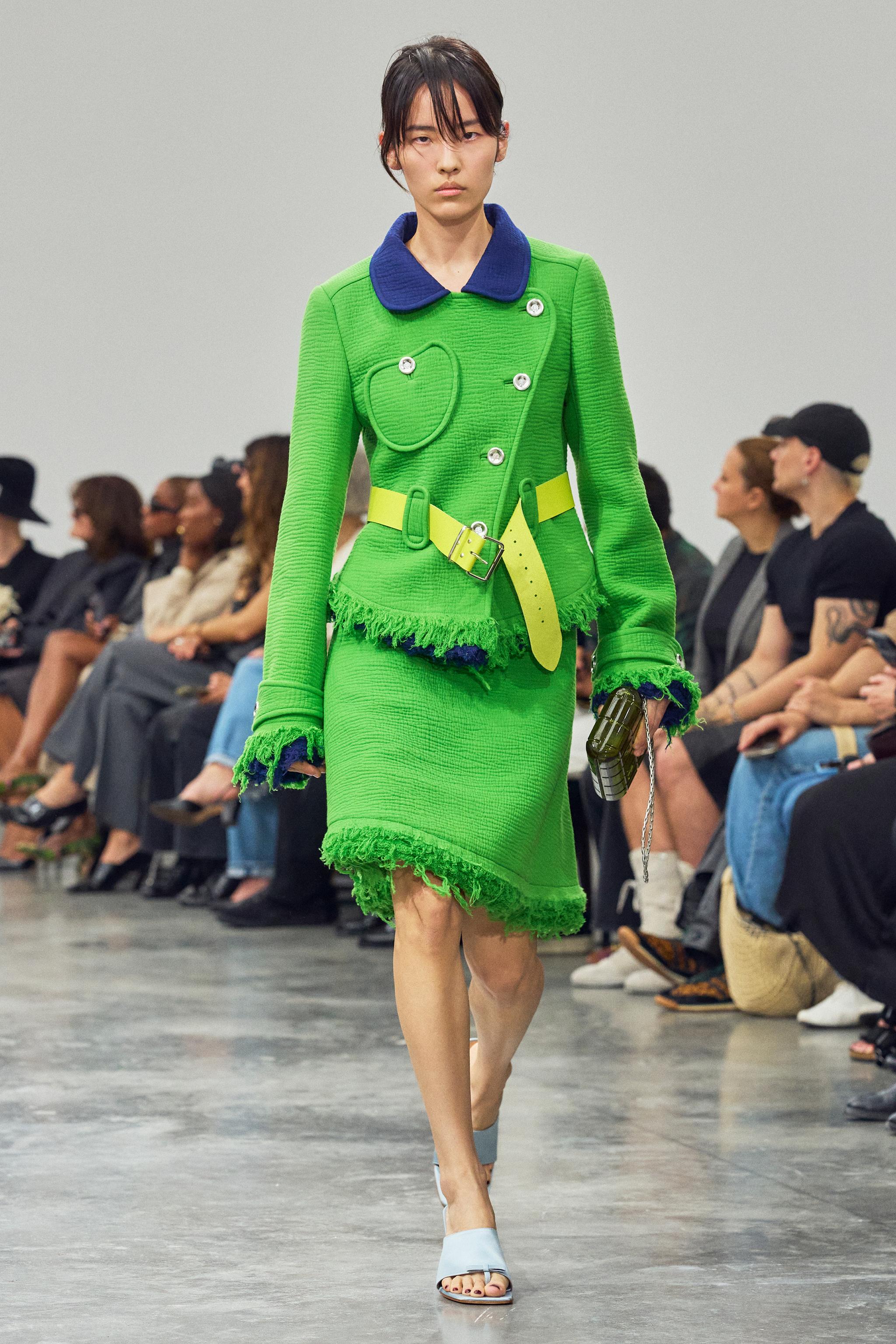 Elegant green and navy color-blocked textured jacket and skirt set by Courrèges on runway.