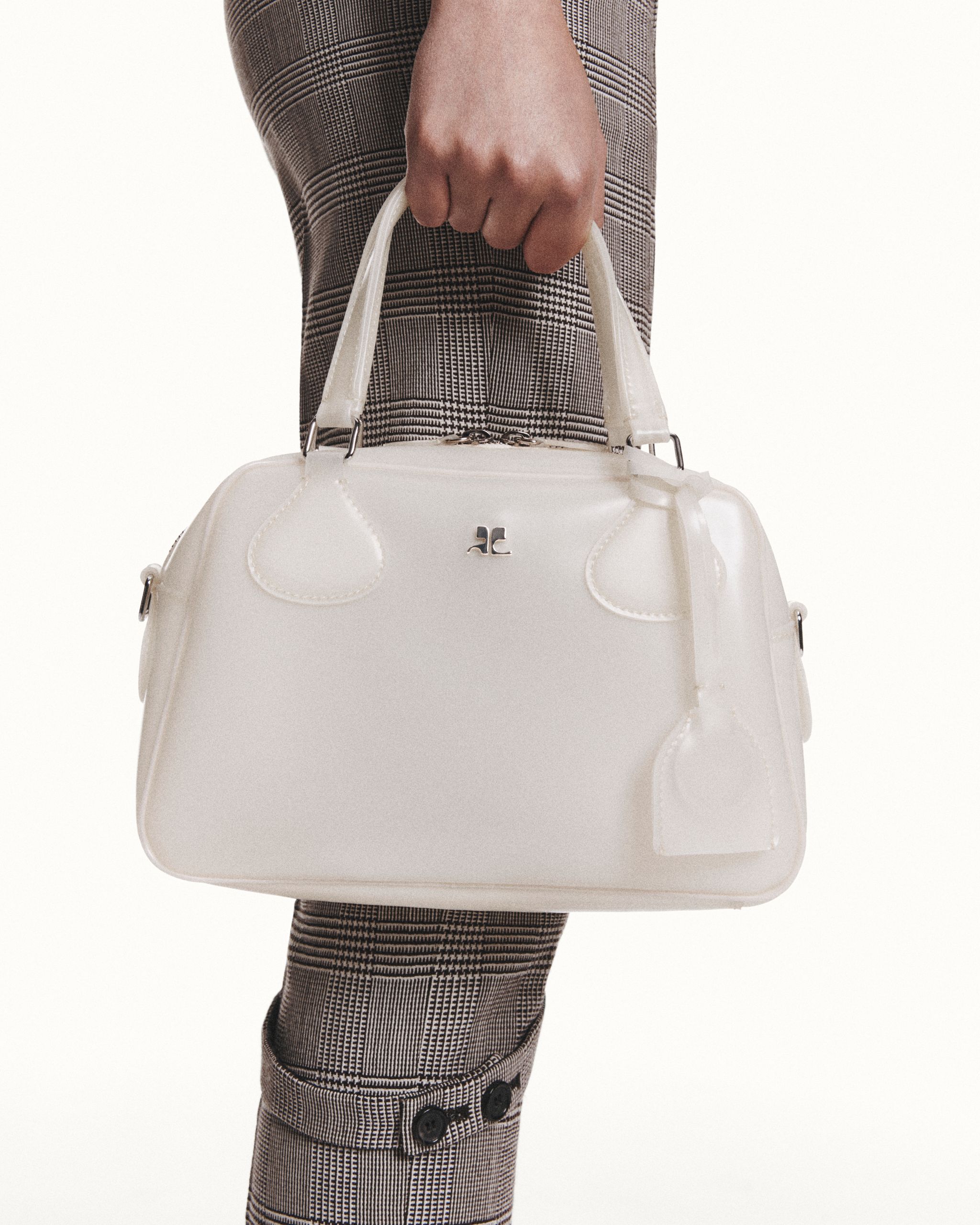 Elegant white handbag from Courrèges on a fashionable person, perfect for an e-commerce site.