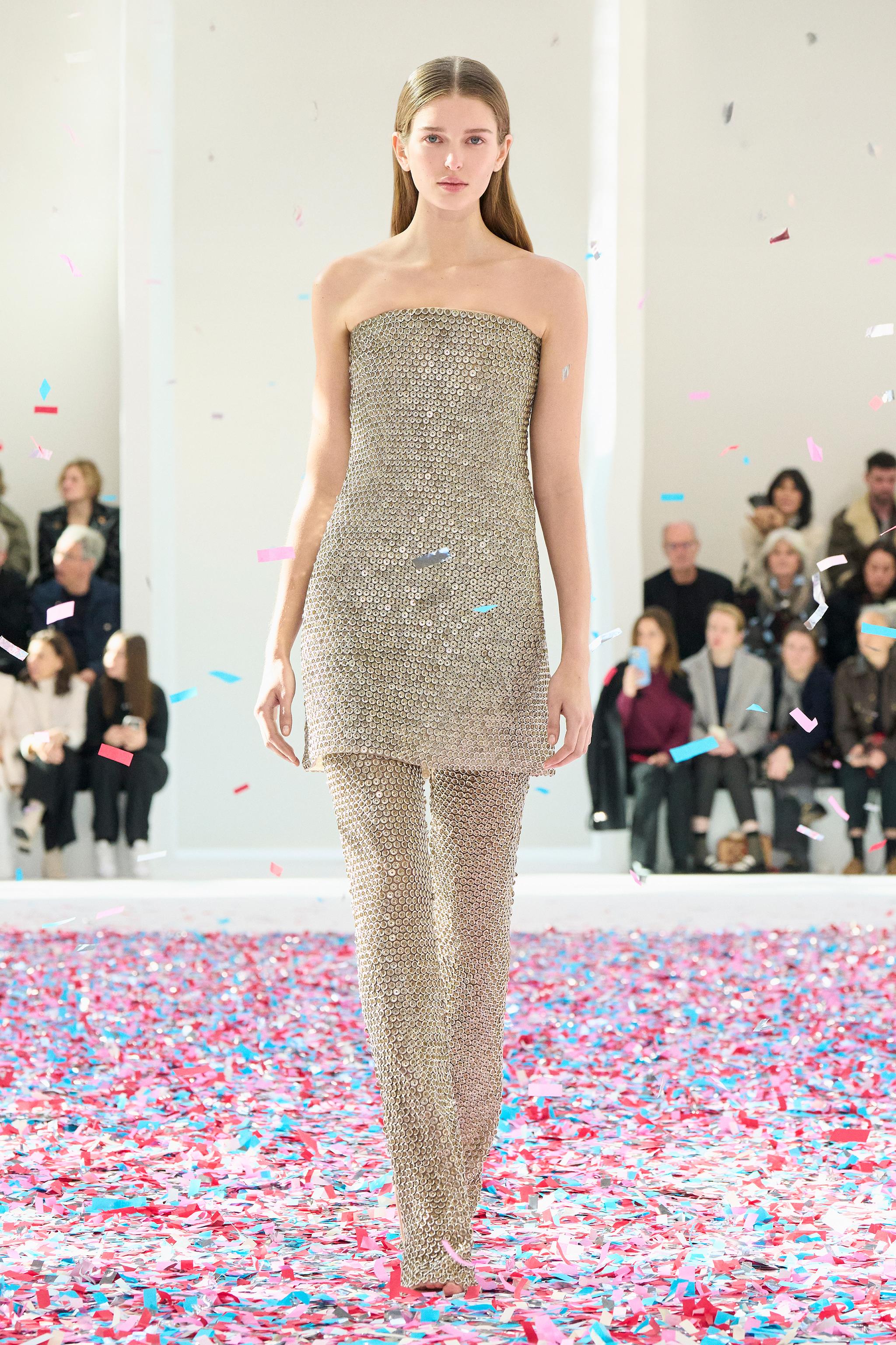 Elegant women's fashion ensemble by Courrèges showcased on a runway with confetti.