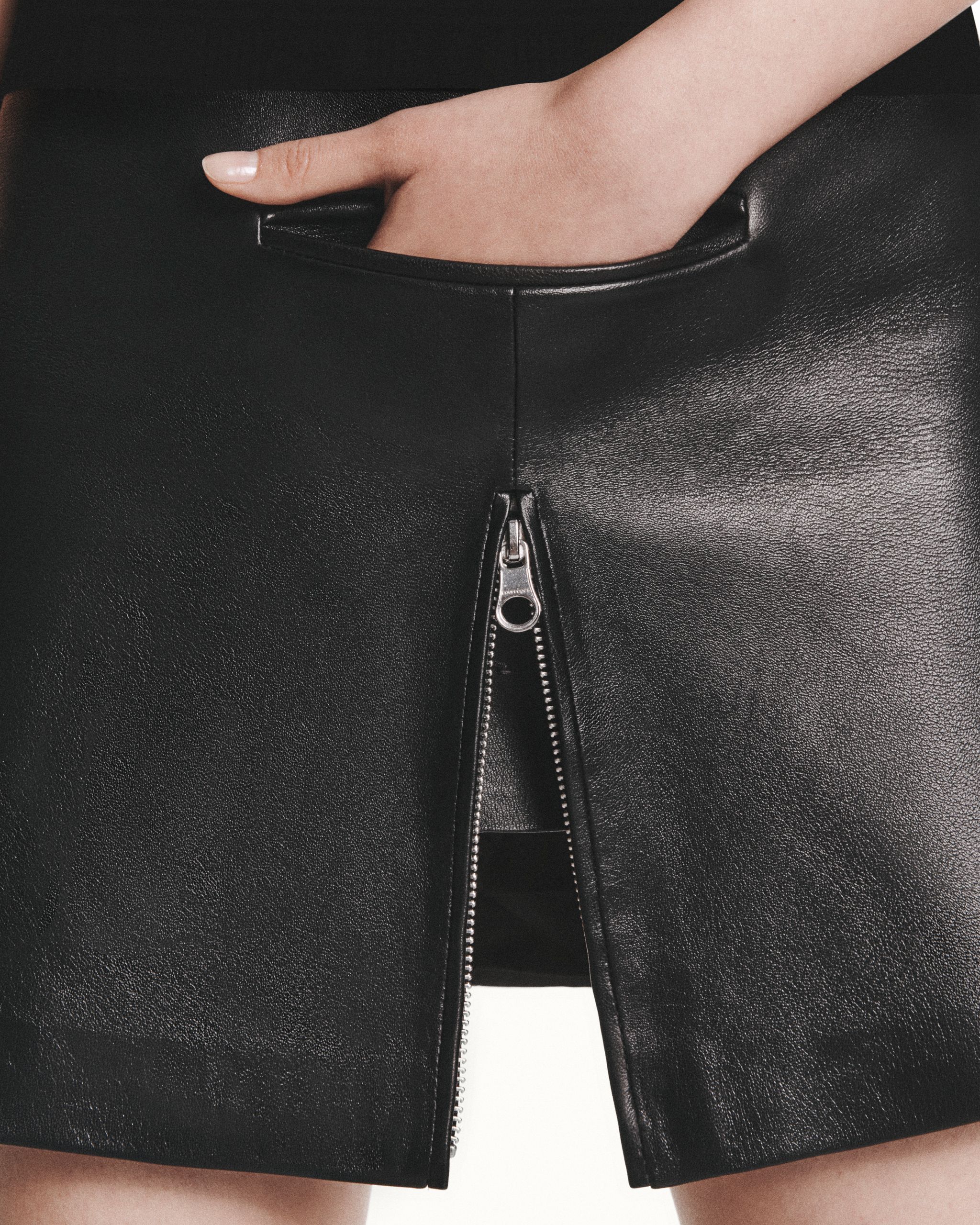 Elegant black leather skirt with front zipper, designed for Courrèges fashion collection.