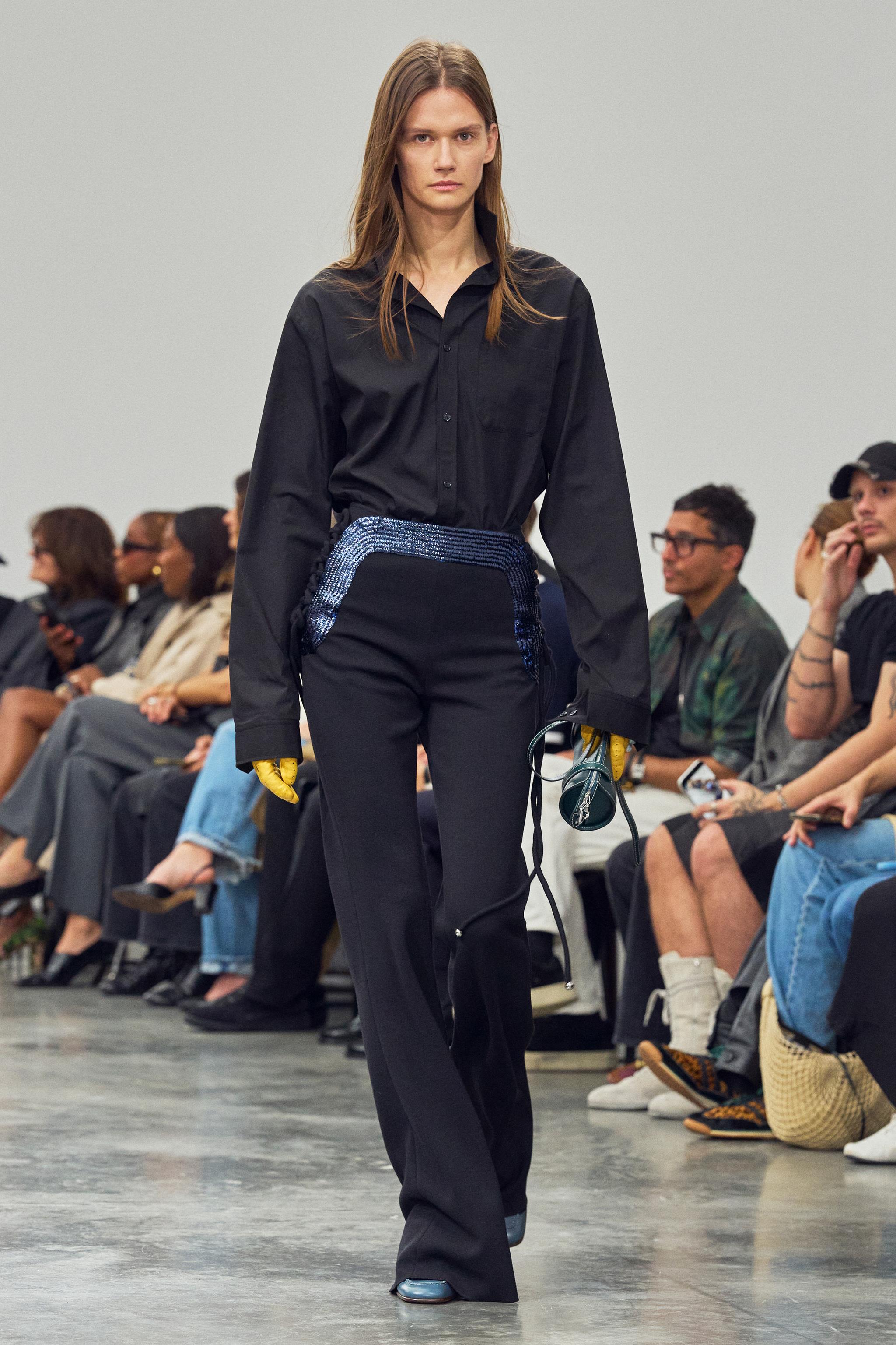 Elegant black shirt with sequined waist detail showcased on a runway for Courrèges fashion.