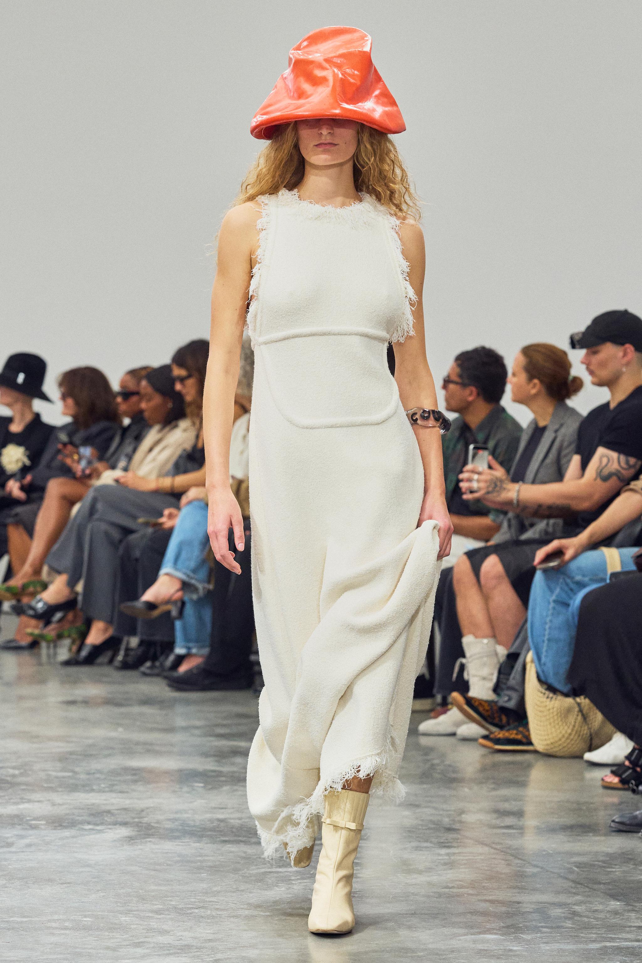 Elegant white dress with fringe details, showcased by a model at Courrèges fashion show.