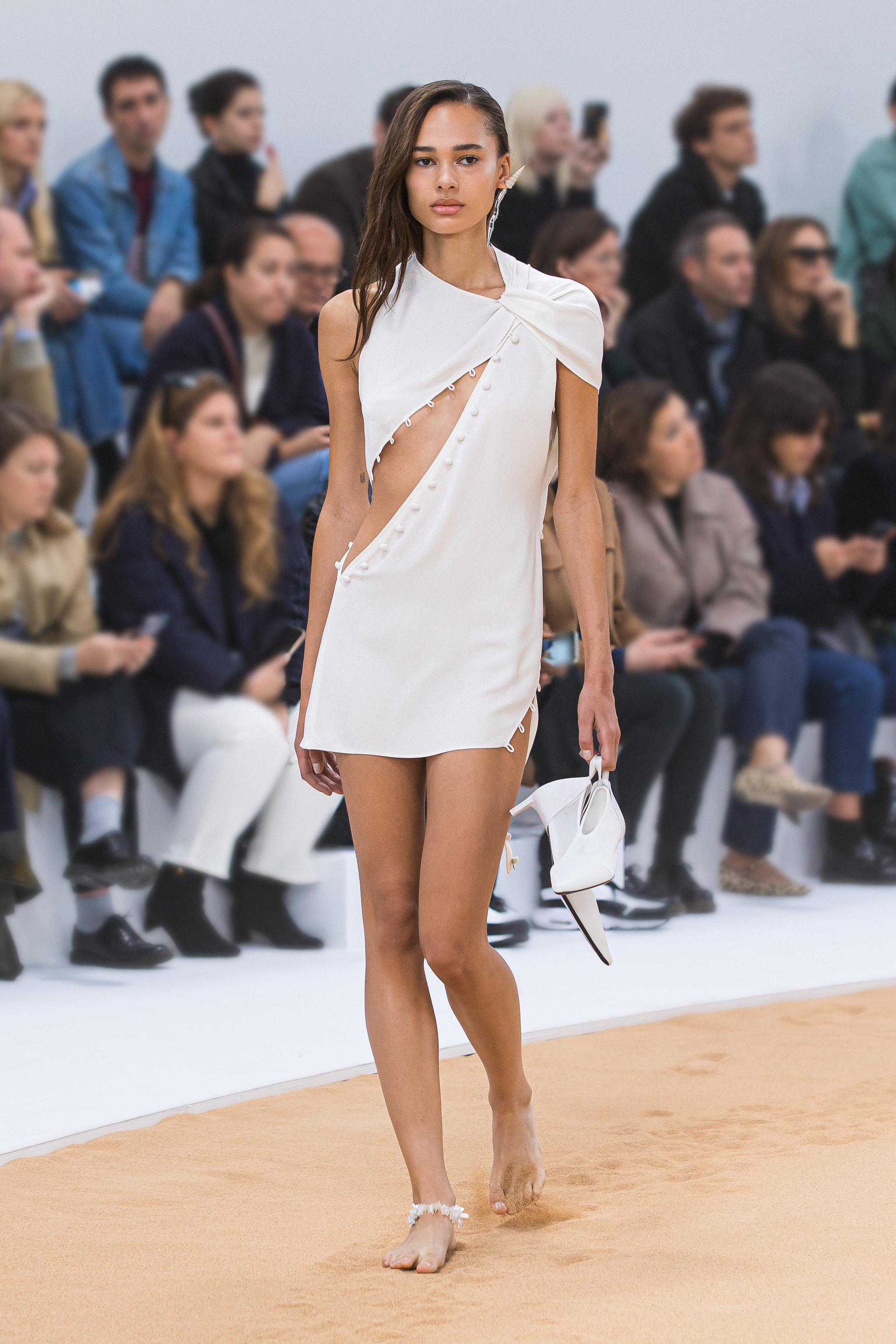 Robe blanche élégante au design asymétrique, présentée lors d'un défilé Courrèges sur le runway.