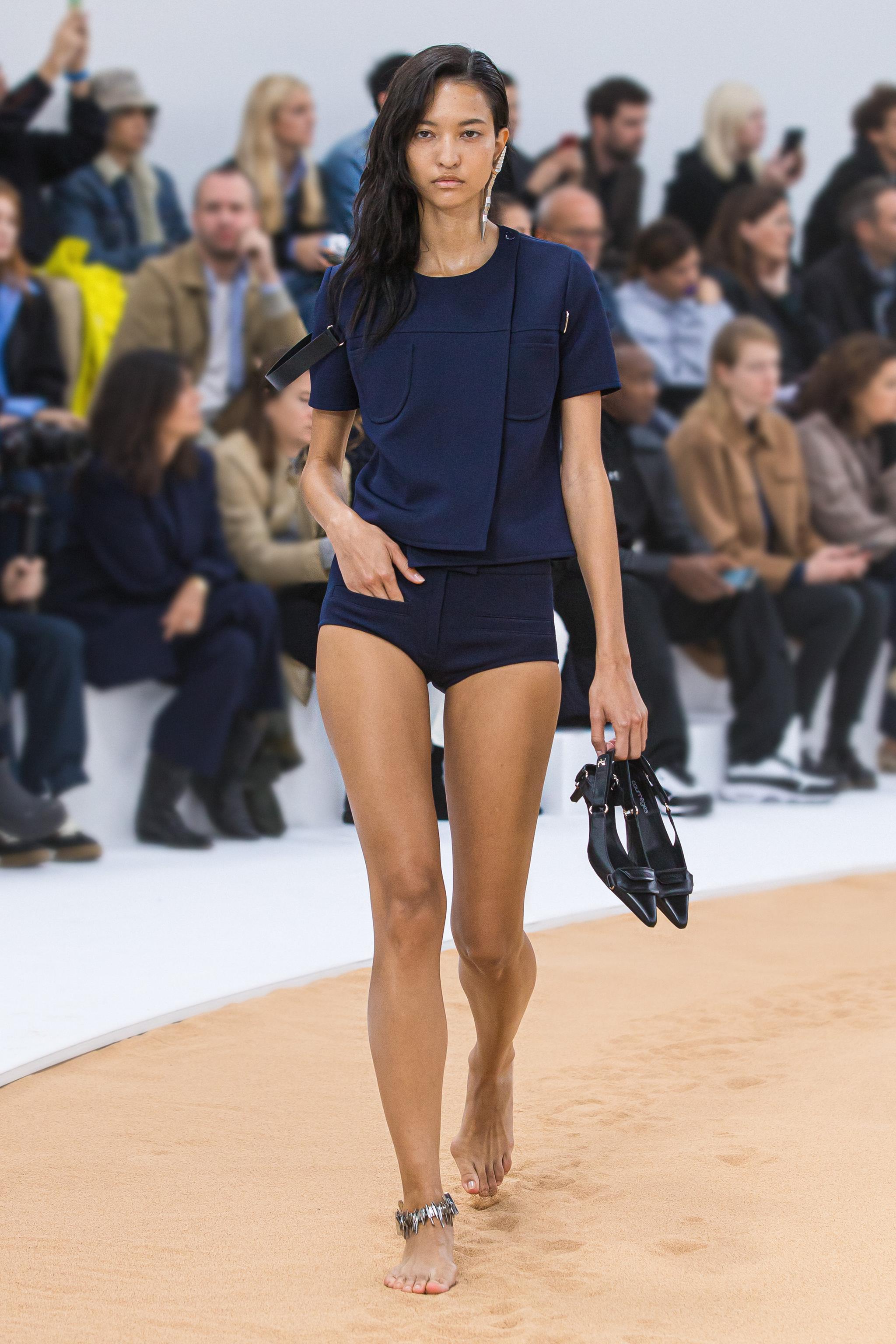 Modèle élégant présente la mode Courrèges sur runway, mettant en valeur une tenue moderne et chic.
