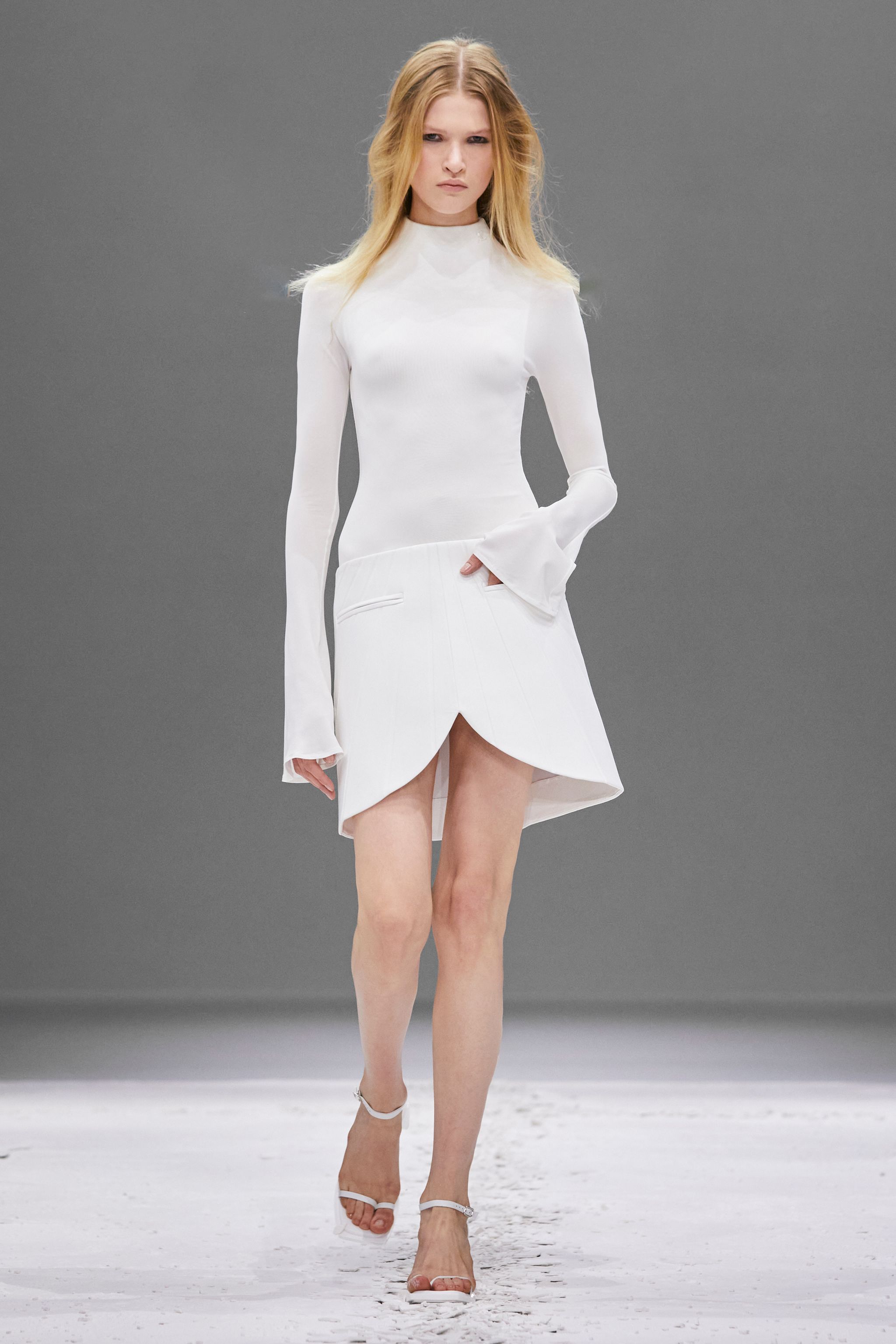 Elegant white dress and skirt ensemble from Courrèges on a runway, highlighting modern fashion.