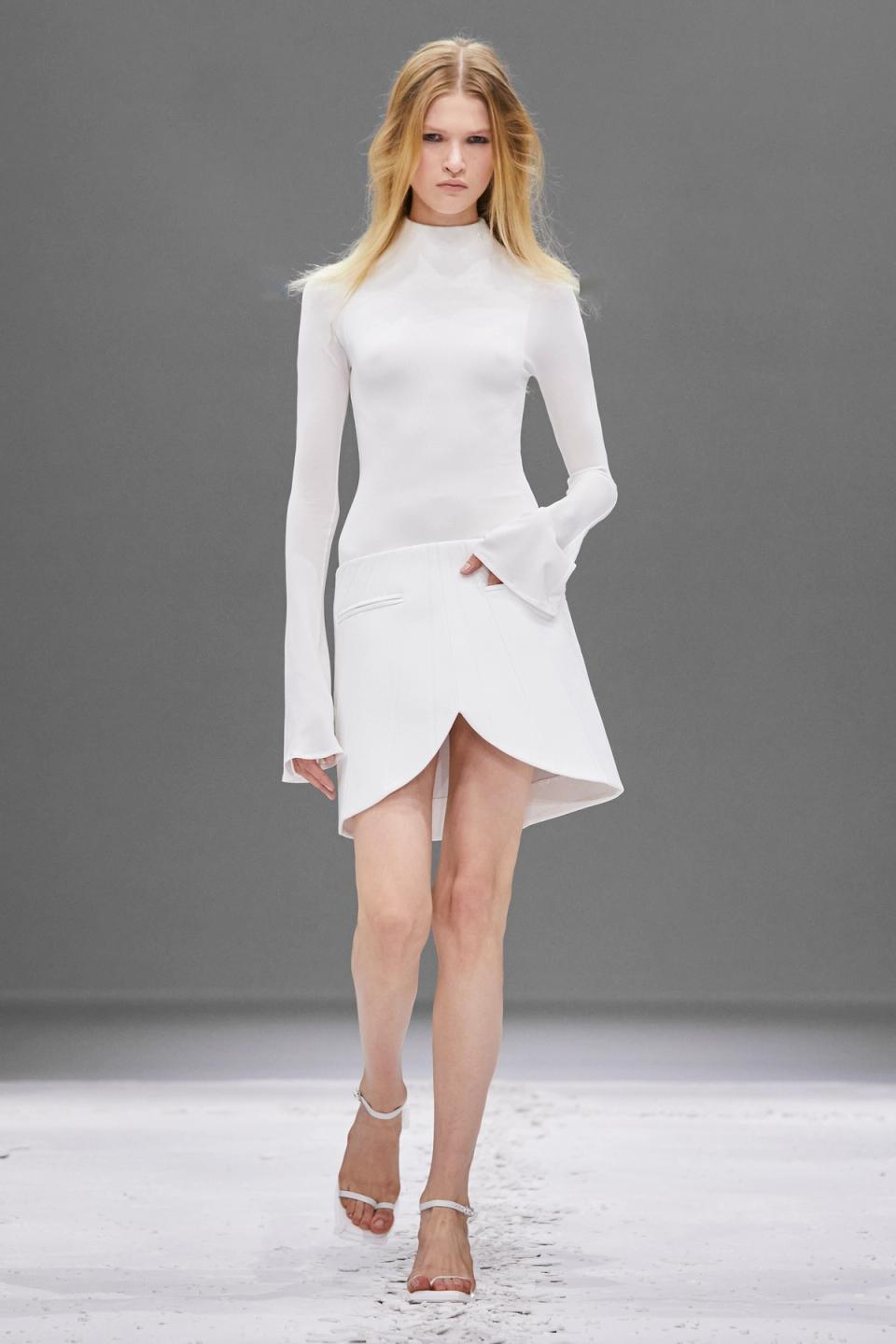 Elegant white dress and skirt ensemble from Courrèges on a runway, highlighting modern fashion.