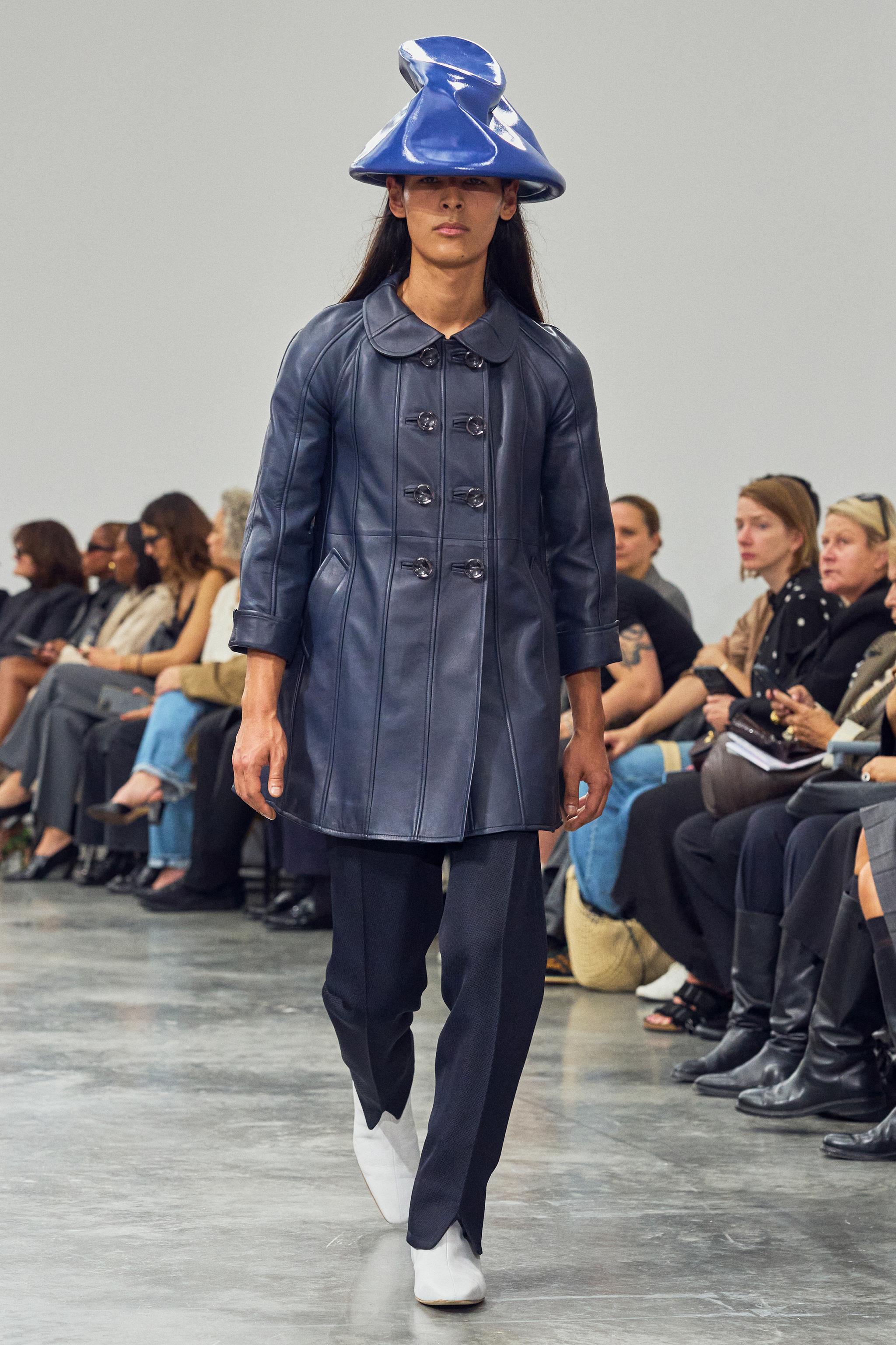 Elegant blue leather trench coat with hat, featured on a runway for Courrèges fashion show.