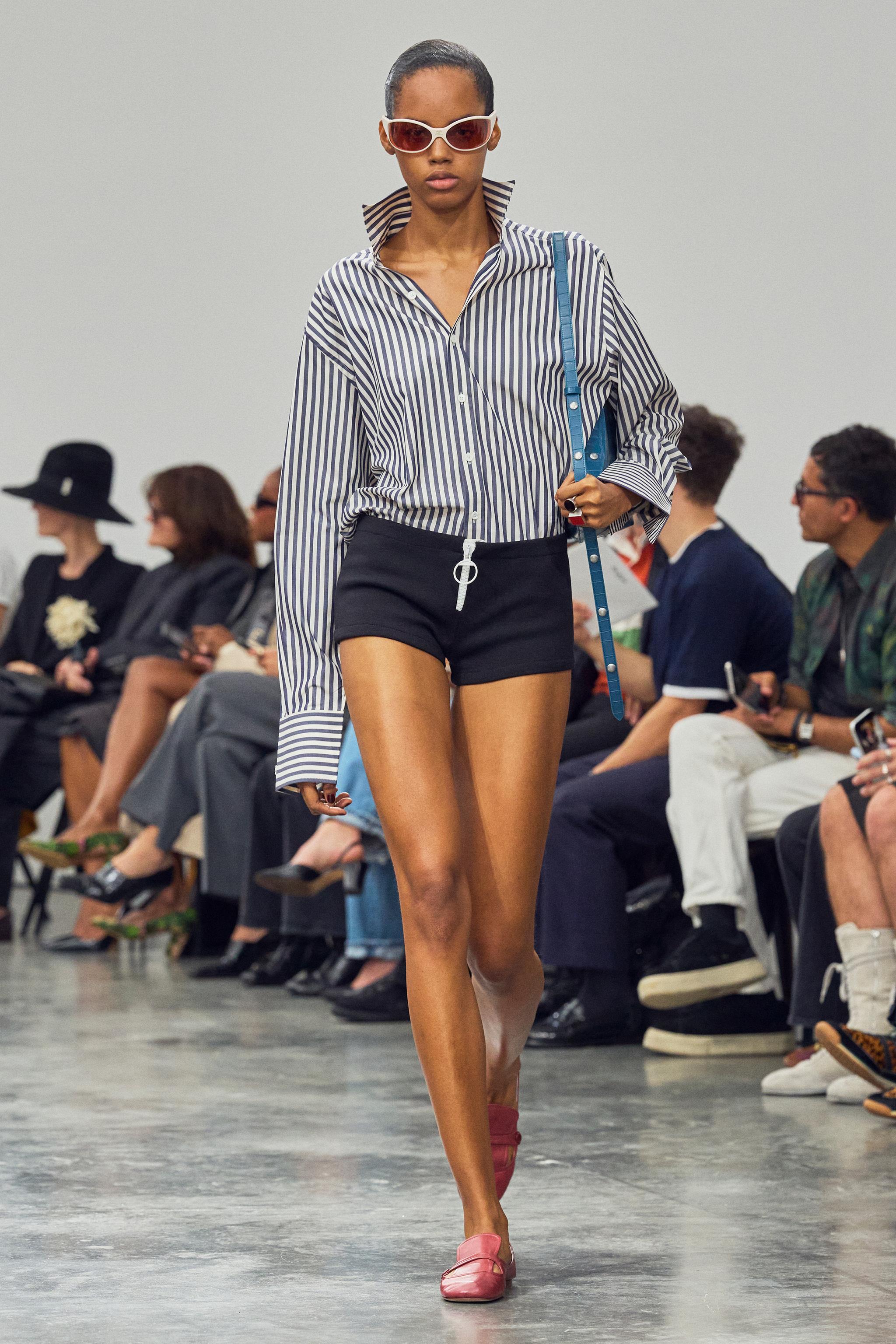 Elegant model walks runway showcasing Courrèges fashion at a minimalist runway show.