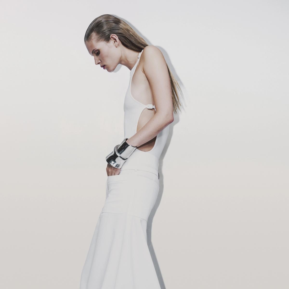 Elegant white Courrèges outfit with a unique cut design, showcased on a model for fashion website.