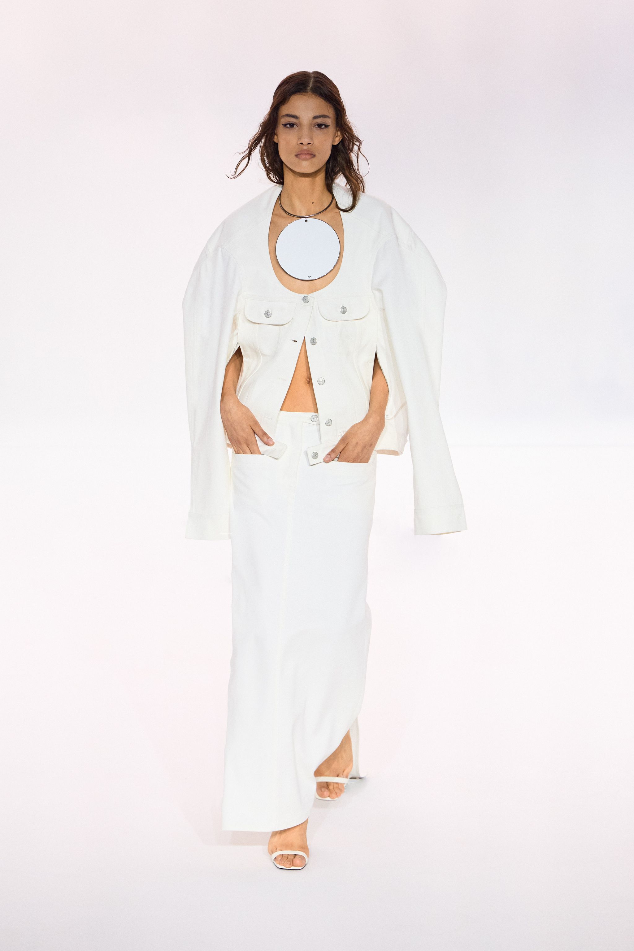 Elegant white fashion ensemble by Courrèges featuring a jacket, skirt, and modern accessories.