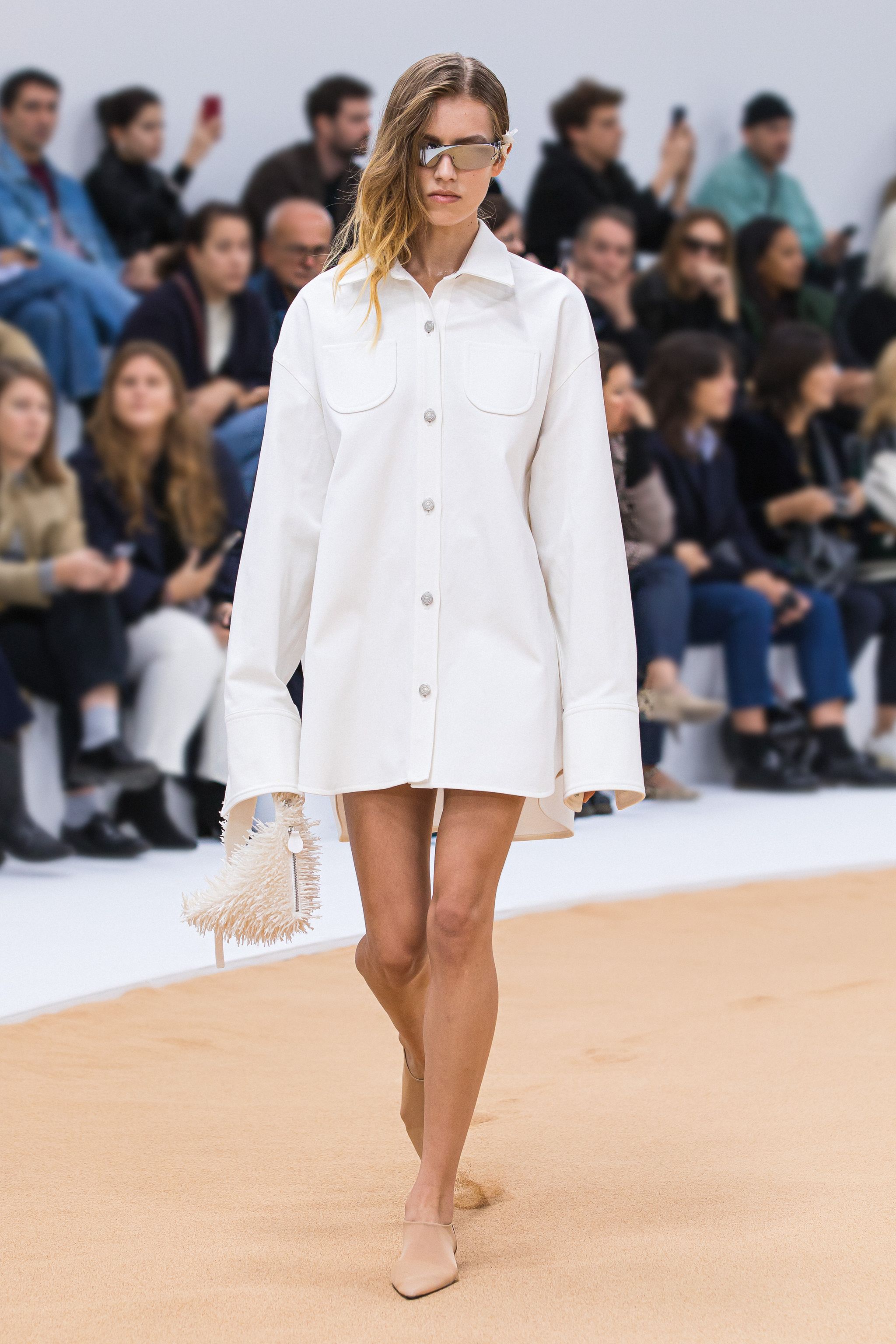 Elegant runway model in white shirt dress with futuristic sunglasses for Courrèges fashion.