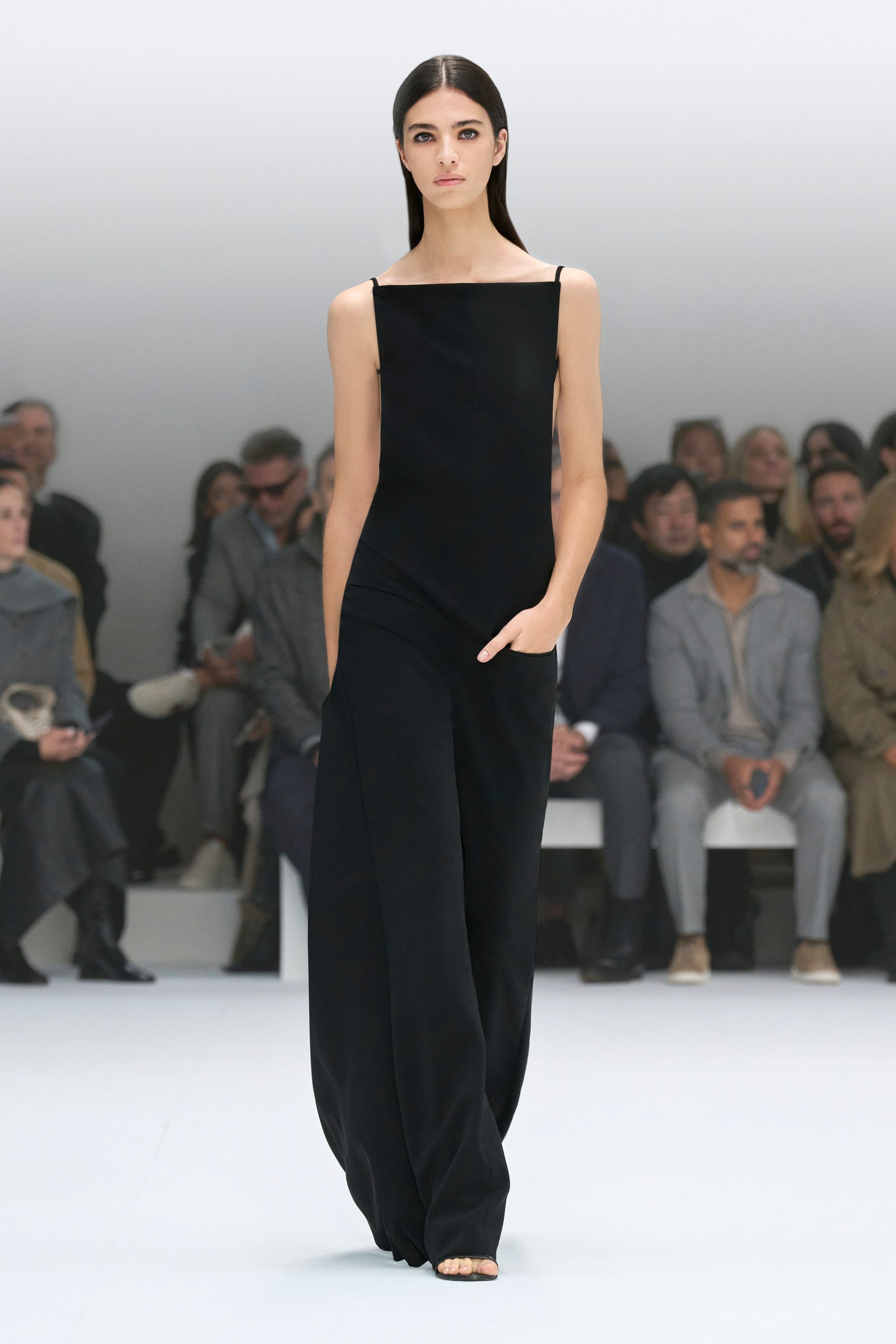 Elegant black fashion jumpsuit showcased by a model on Courrèges runway in a sleek setting.
