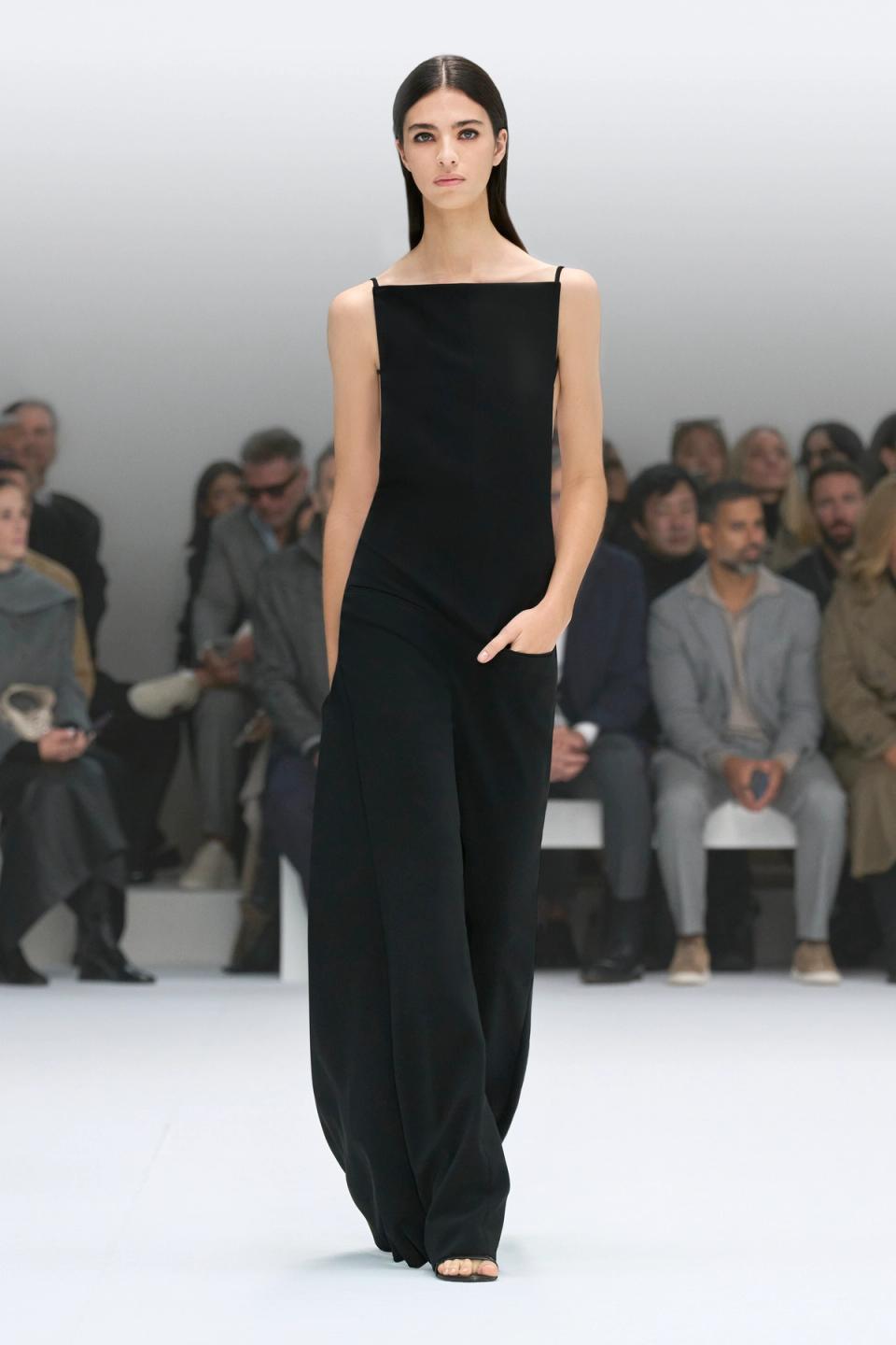 Elegant black fashion jumpsuit showcased by a model on Courrèges runway in a sleek setting.