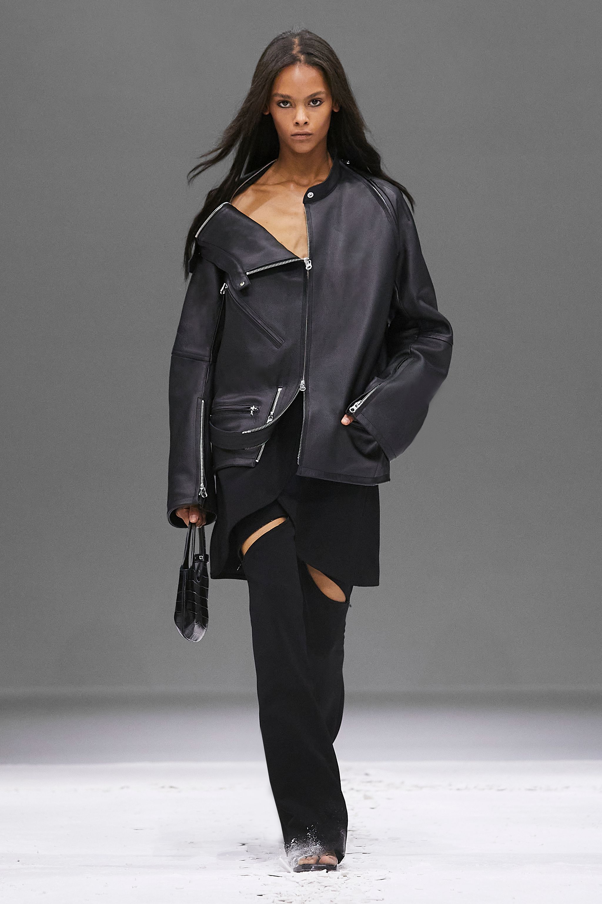 Elegant model wearing a black leather jacket on a fashion runway for Courrèges.