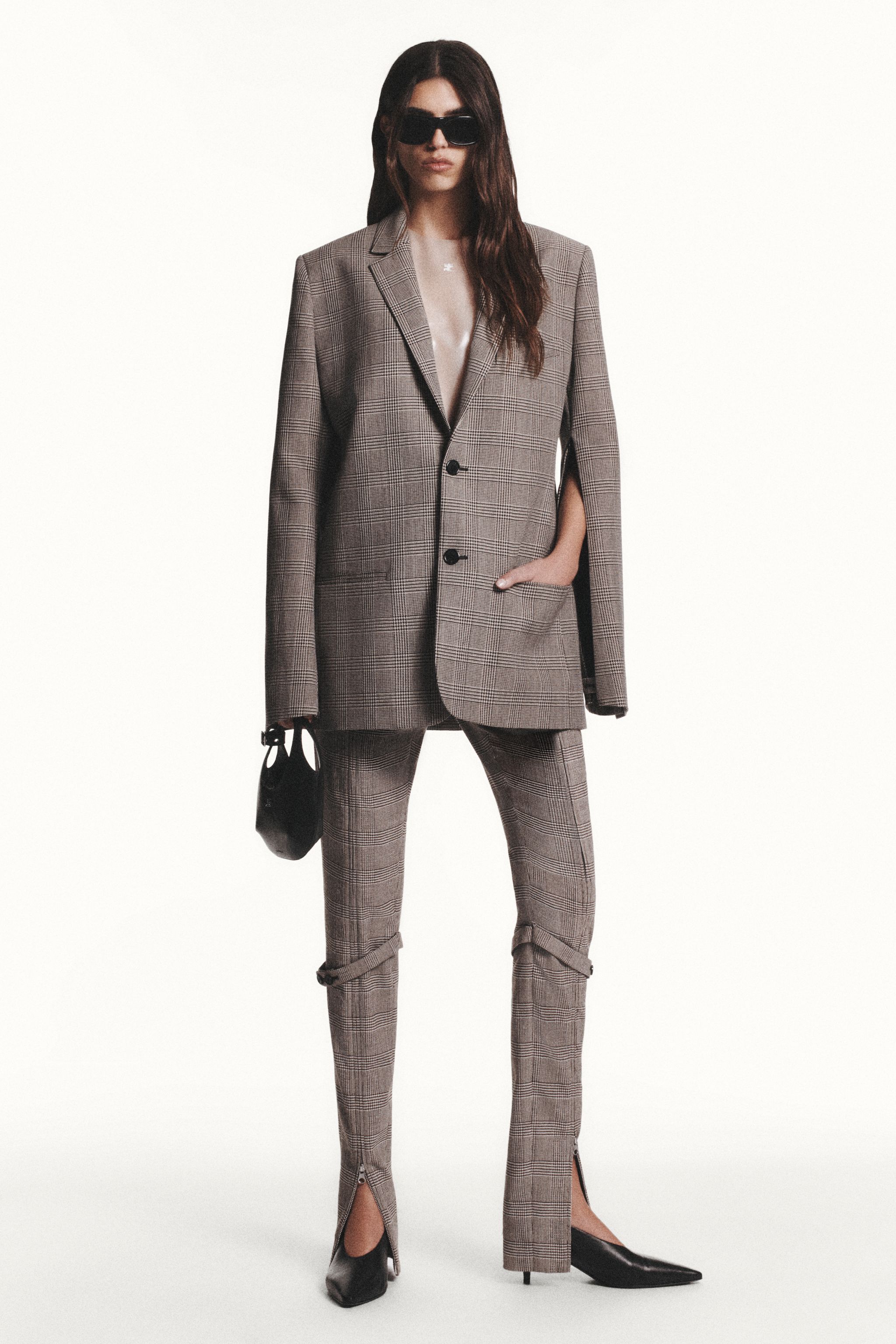 Elegant woman in checked blazer and matching pants, wearing sunglasses, for Courrèges fashion.