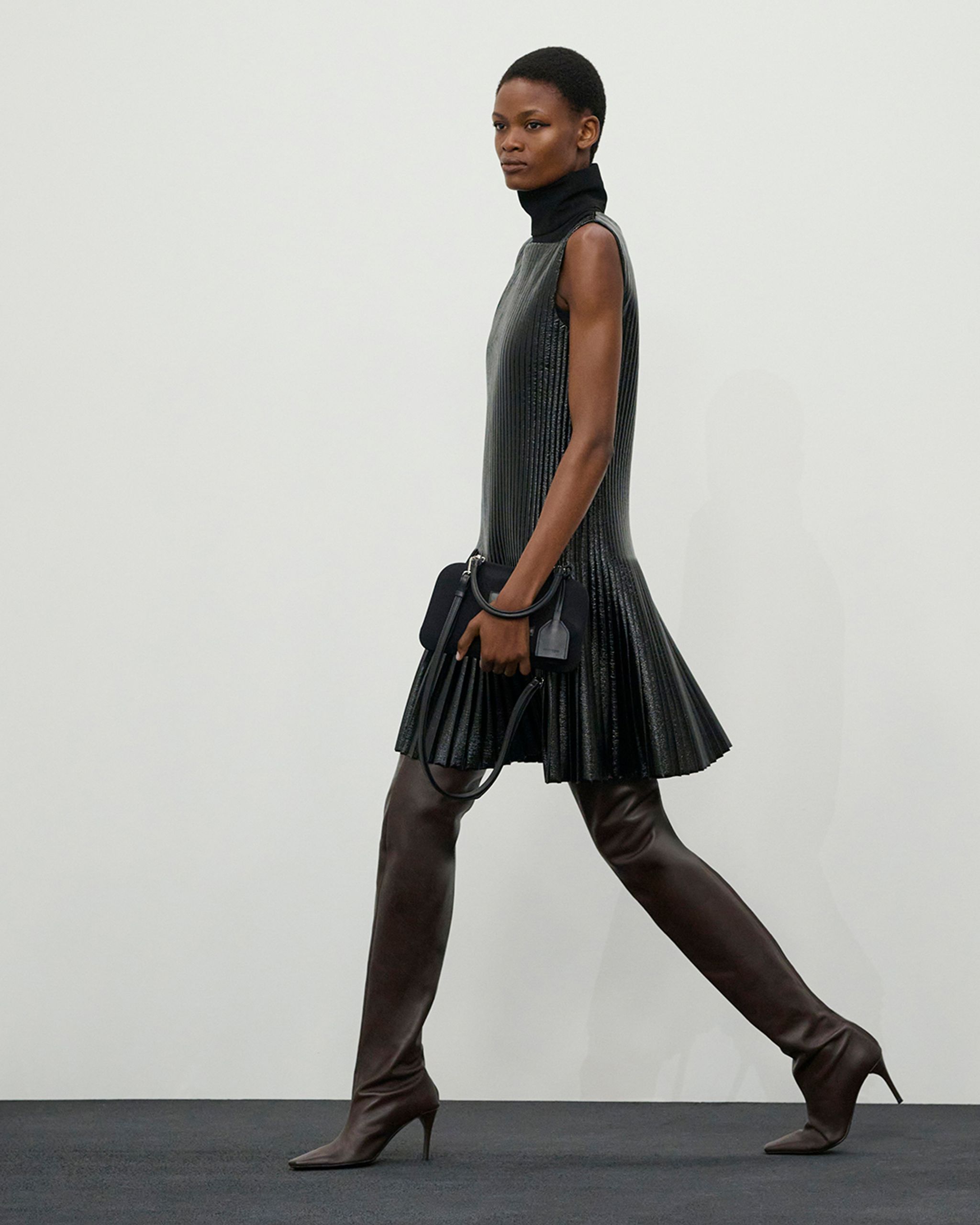 Robe plissée noire élégante avec col roulé haut, présentée par Courrèges pour amateurs de mode.