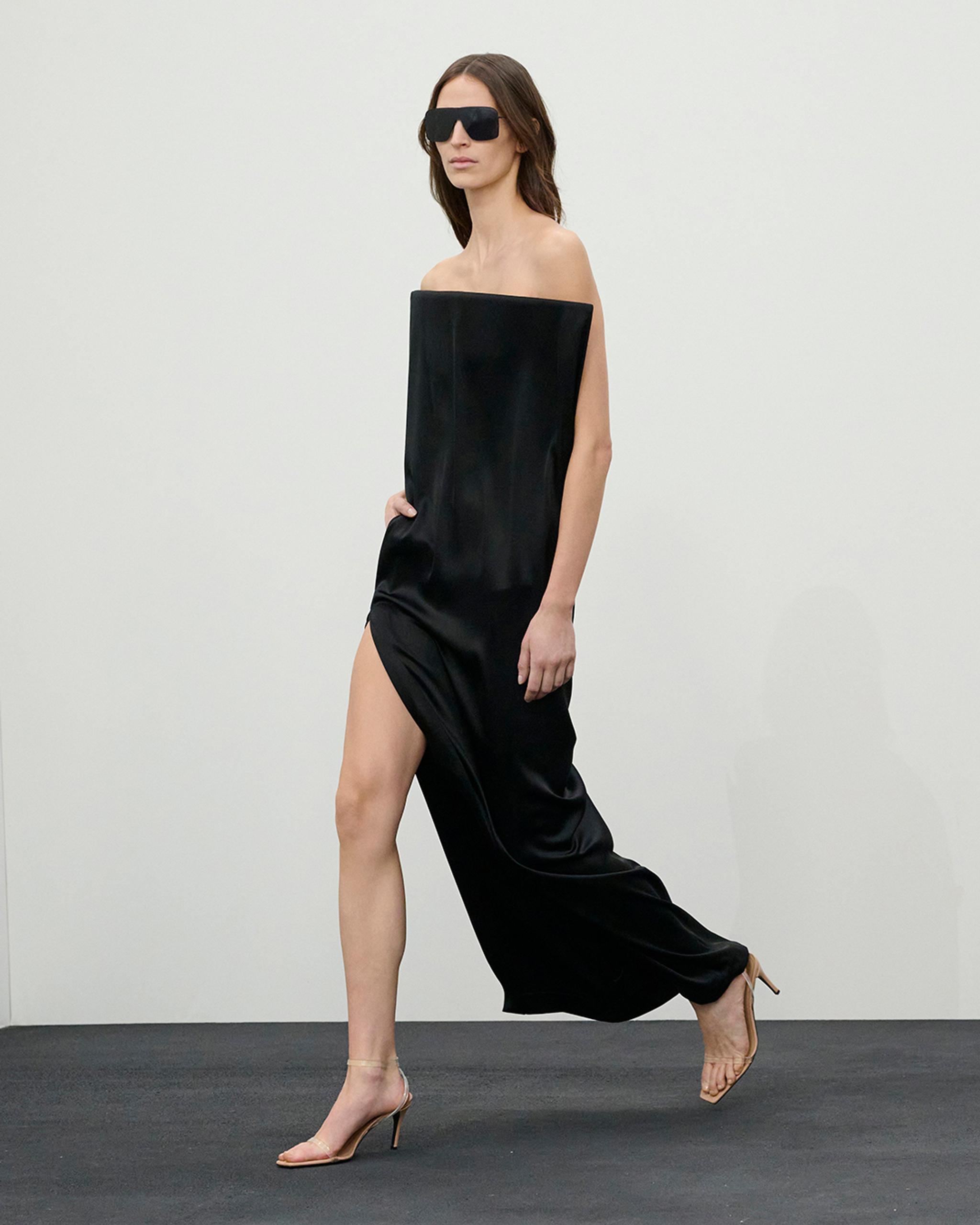 Elegant model in black satin dress with oversized top, sunglasses, and heels for Courrèges.