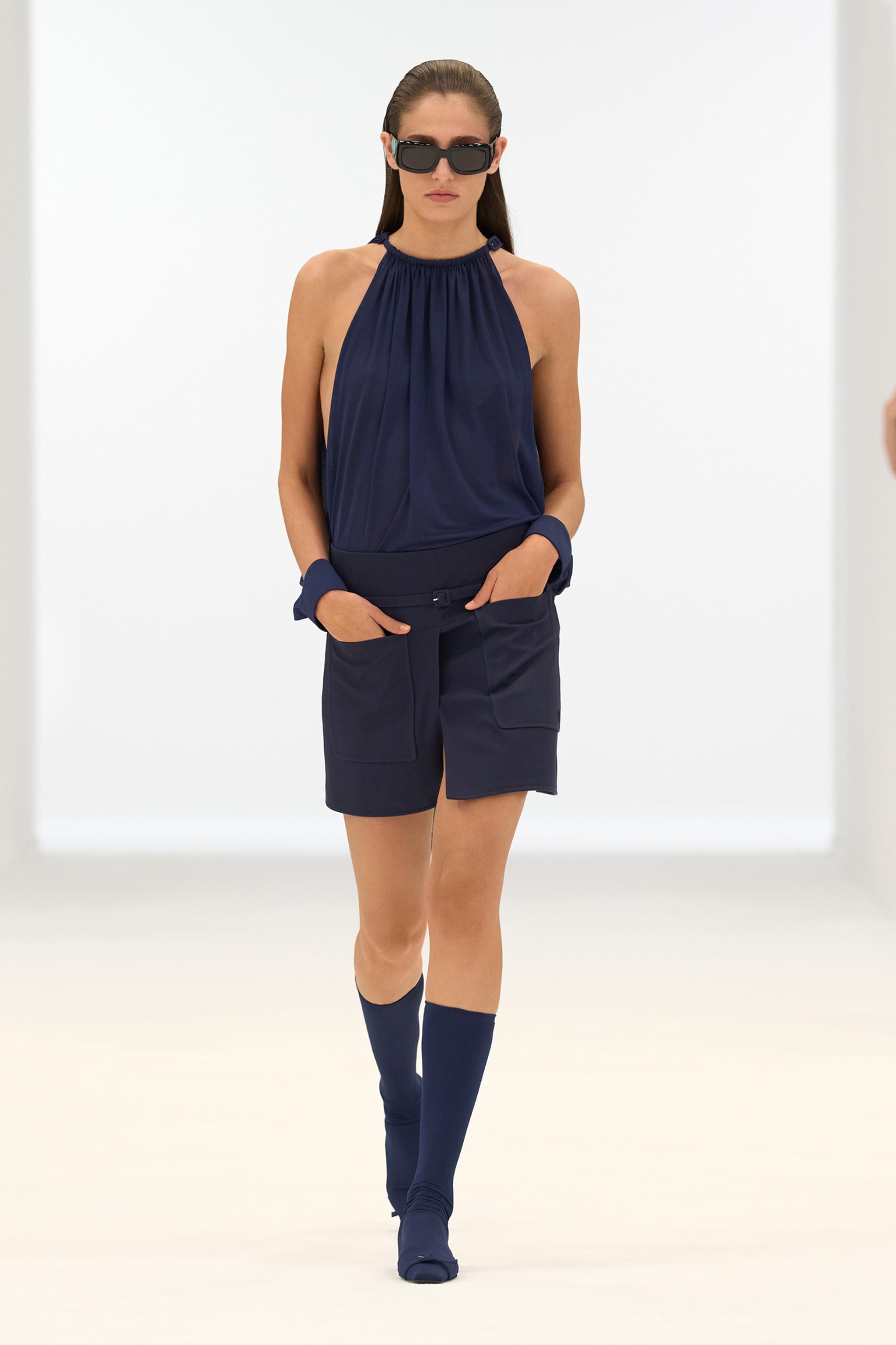 Elegant navy blue outfit with trendy sunglasses, showcased on a fashion runway by Courrèges.