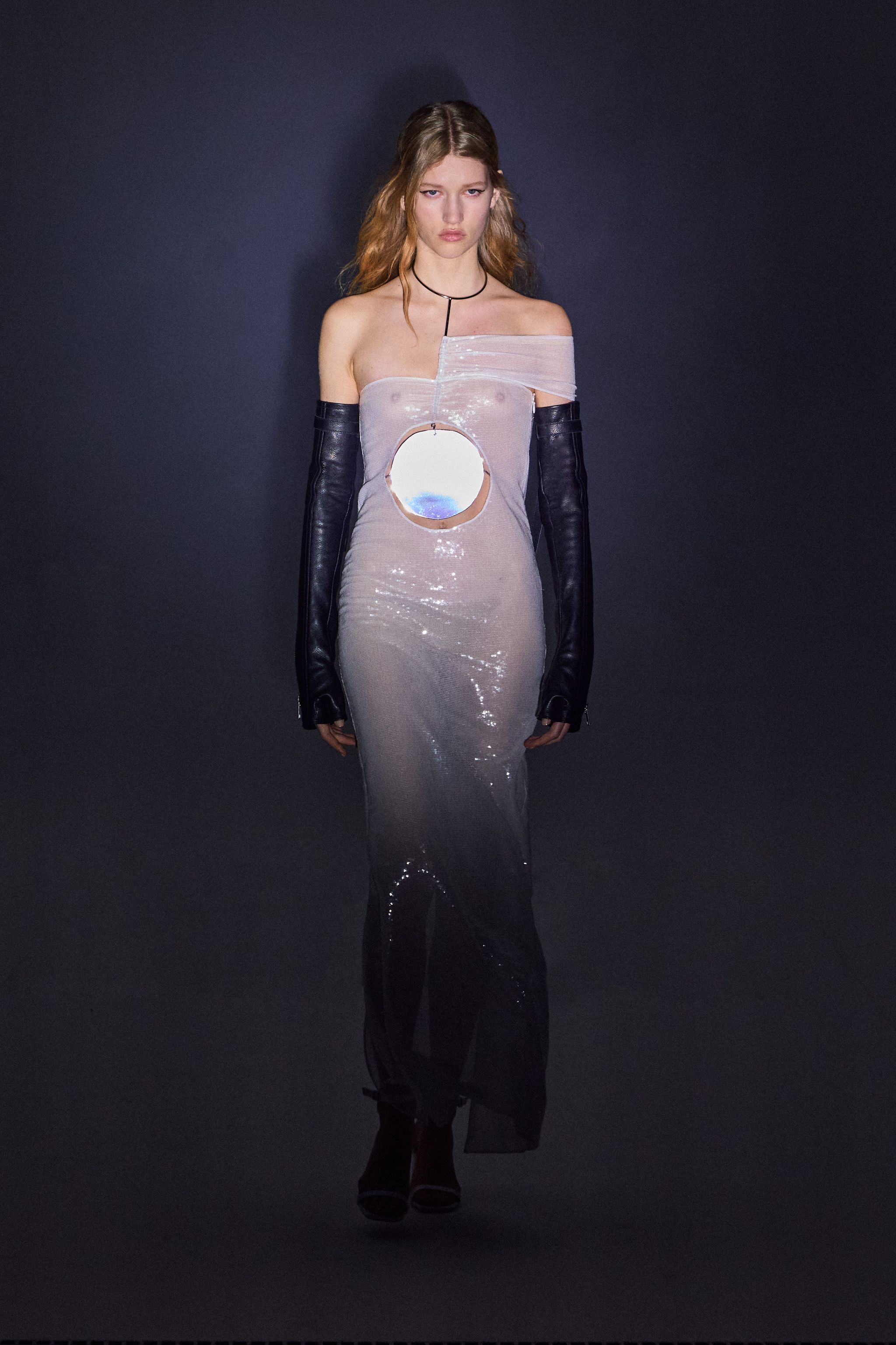 Elegant model wearing a reflective, off-shoulder gown with unique cutout and black gloves, on Courrèges site.