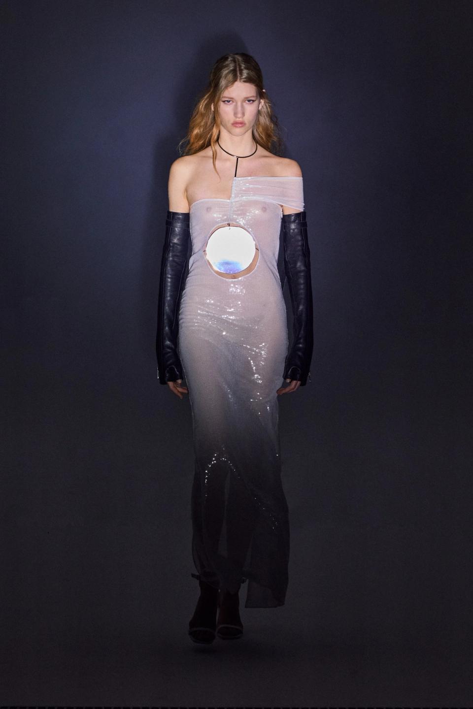 Elegant model wearing a reflective, off-shoulder gown with unique cutout and black gloves, on Courrèges site.