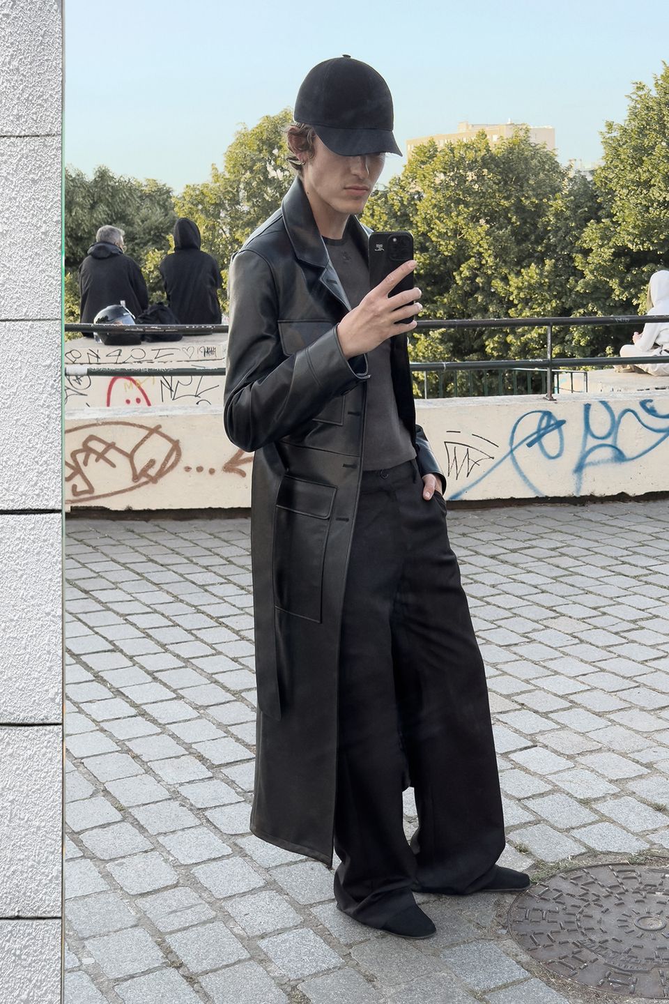 Chic black leather trench coat and cap from Courrèges, perfect for a stylish urban look.
