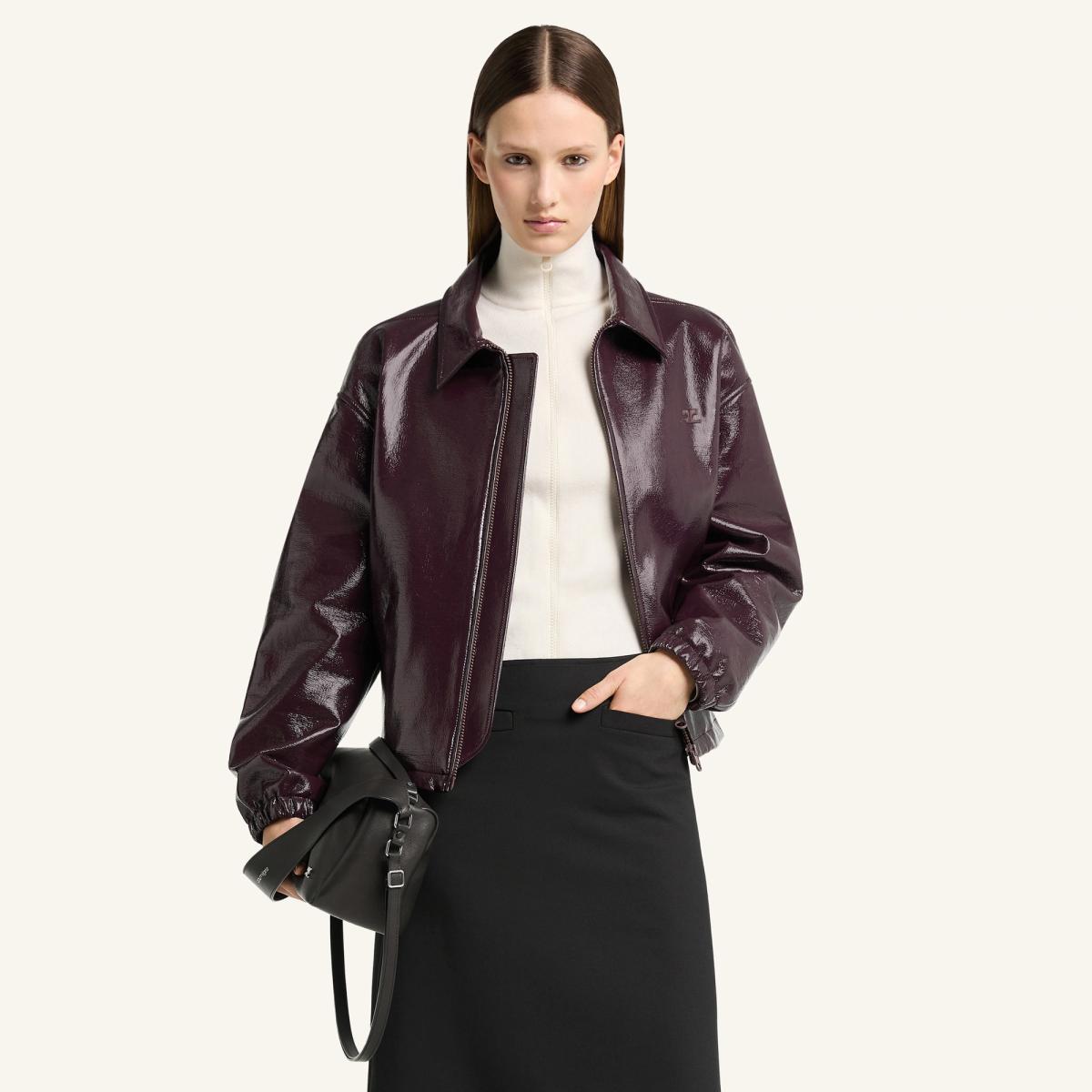 Elegant model wearing a glossy burgundy Courrèges leather jacket, suitable for fashion lovers.
