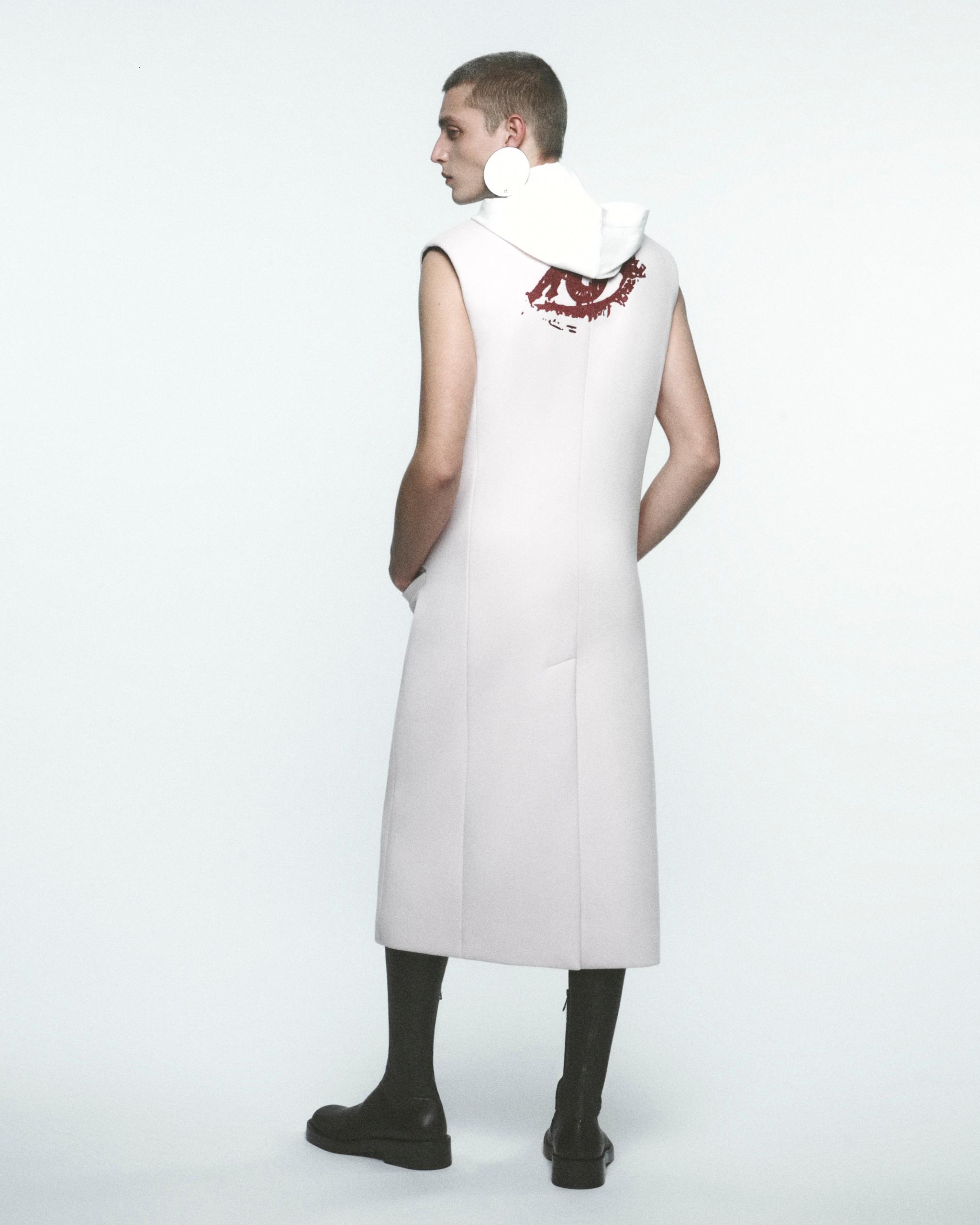 Elegant model wearing a white sleeveless coat with a large print, for Courrèges fashion.
