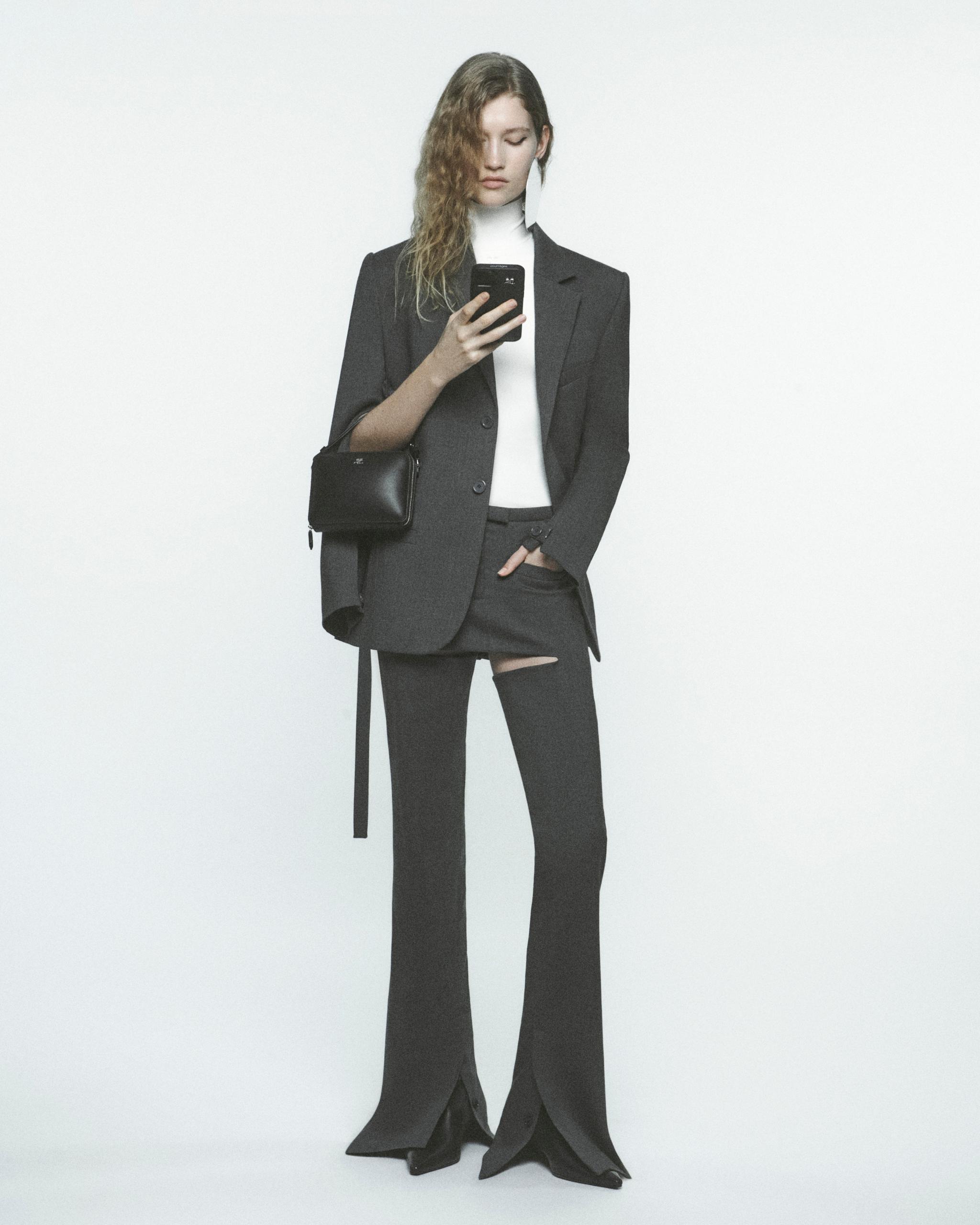 Elegant Courrèges fashion model in a tailored suit and stylish accessories, perfect for ecommerce.