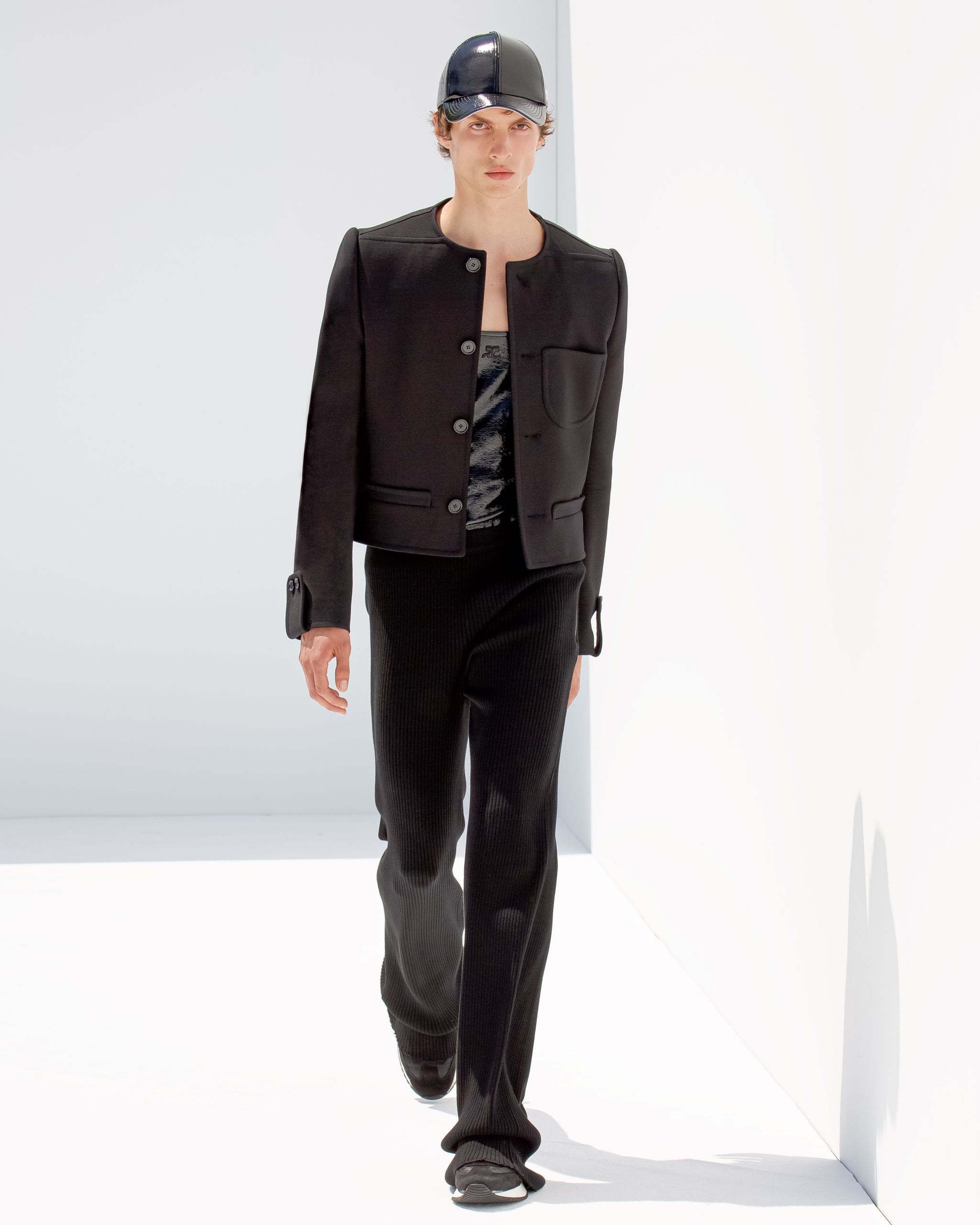 Elegant black jacket and pants showcase Courrèges fashion on a modern runway model.