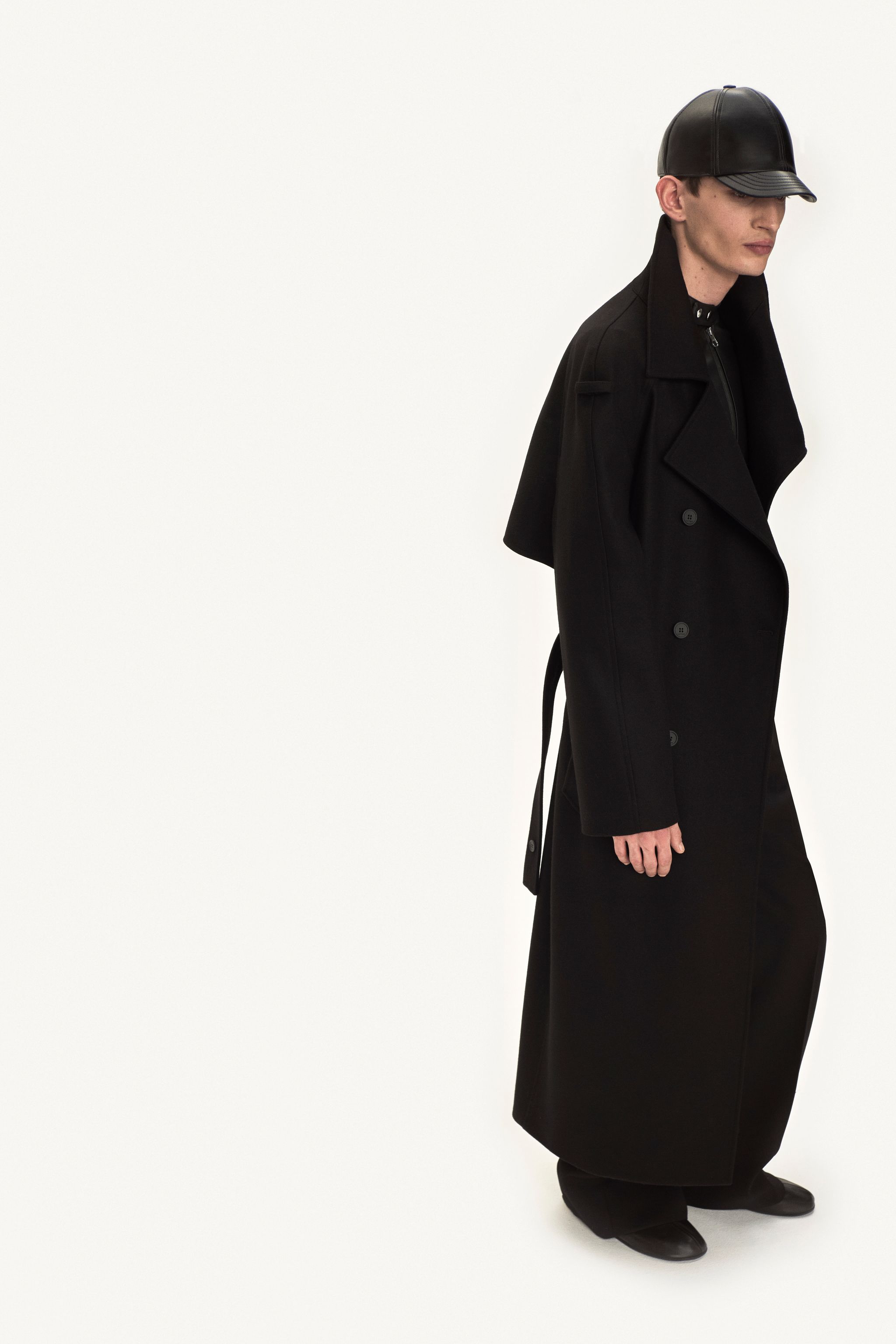 Elegant black trench coat with leather accessories, showcasing Courrèges' modern fashion style.