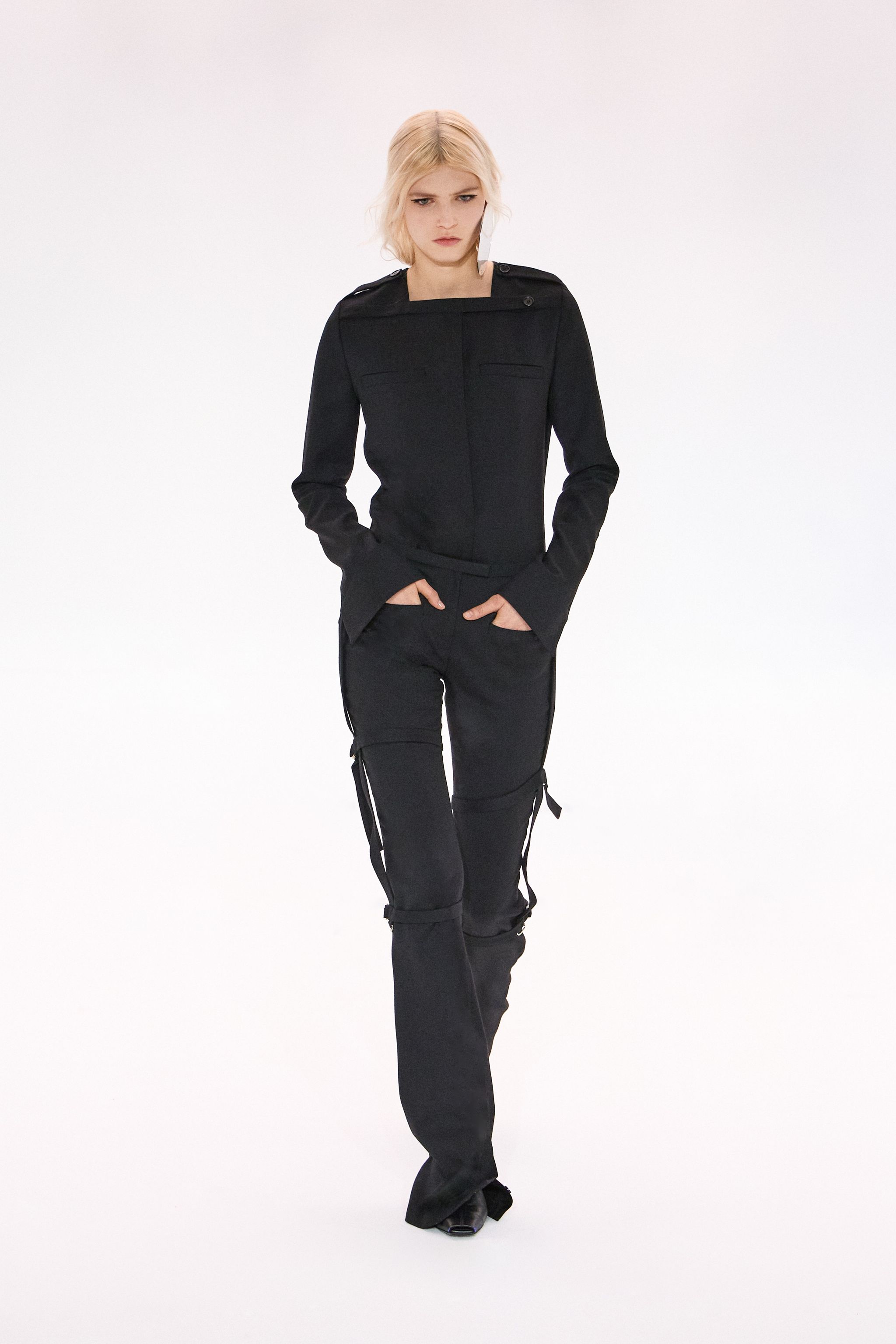 Elegant black fashion jacket and pants from Courrèges displayed on a runway model.