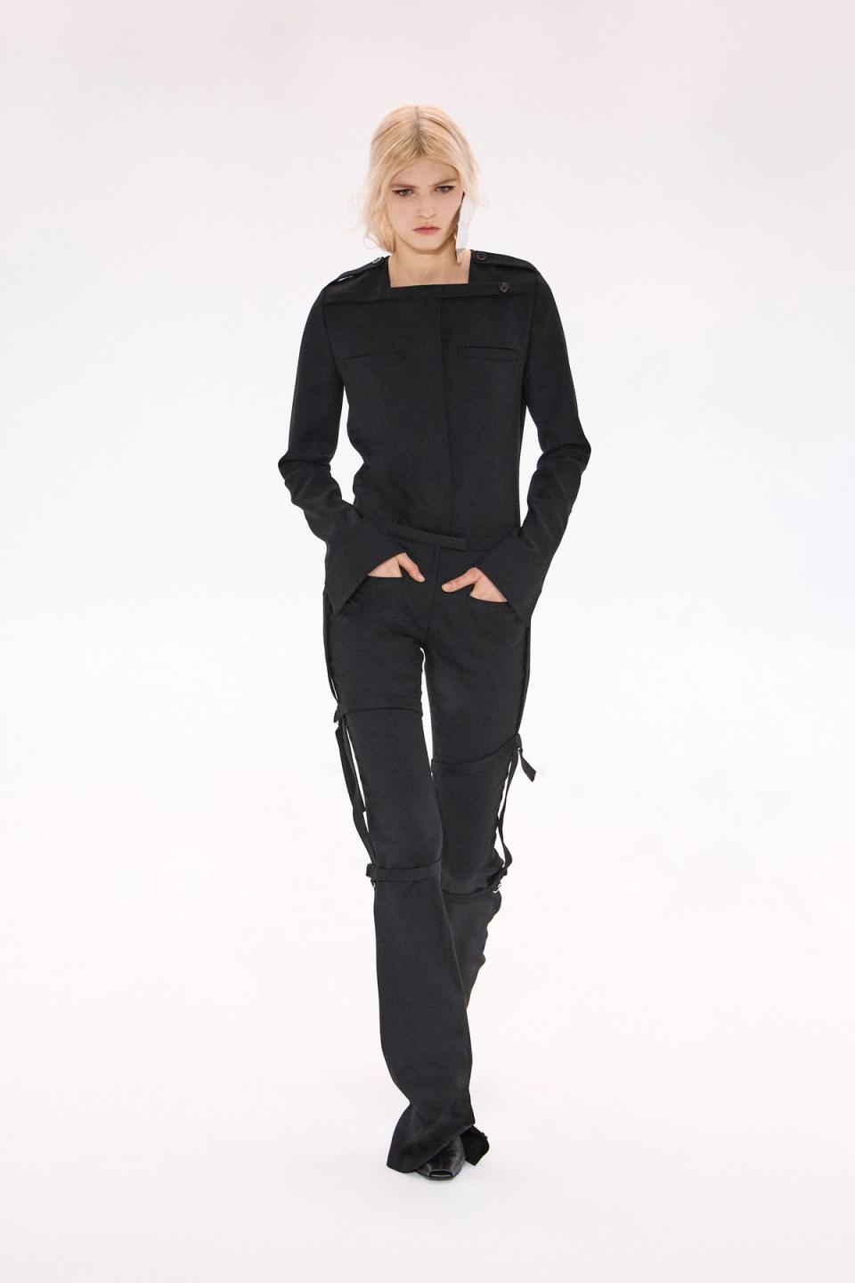 Elegant black fashion jacket and pants from Courrèges displayed on a runway model.