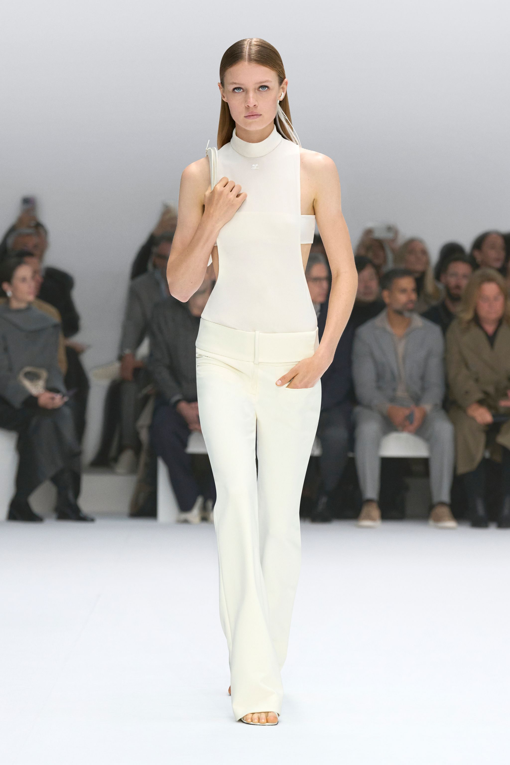 Elegant white sleeveless top and matching pants showcased by a model on Courrèges runway.
