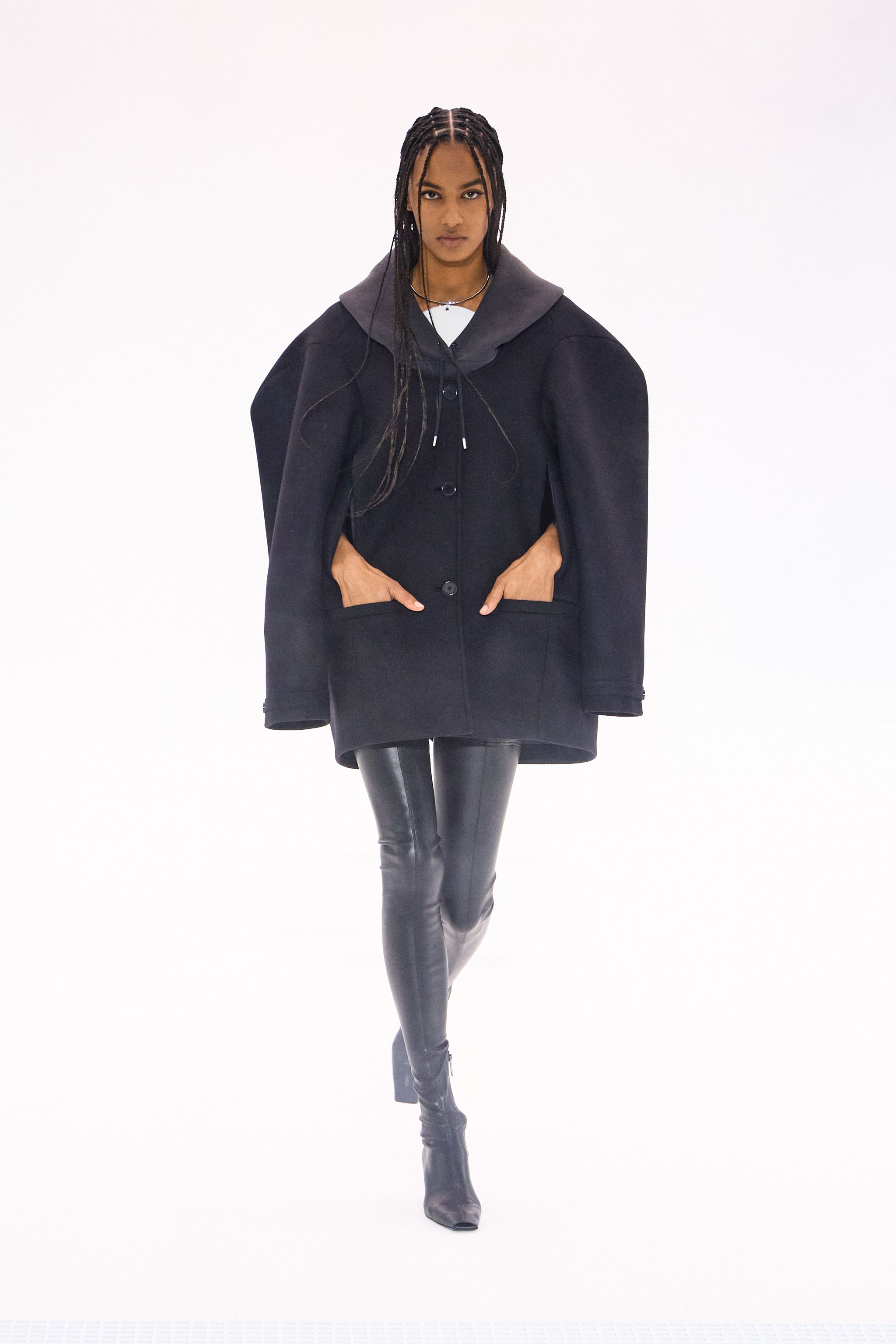 Elegant black shiny leather ensemble with modern style, showcased on a runway for Courrèges.