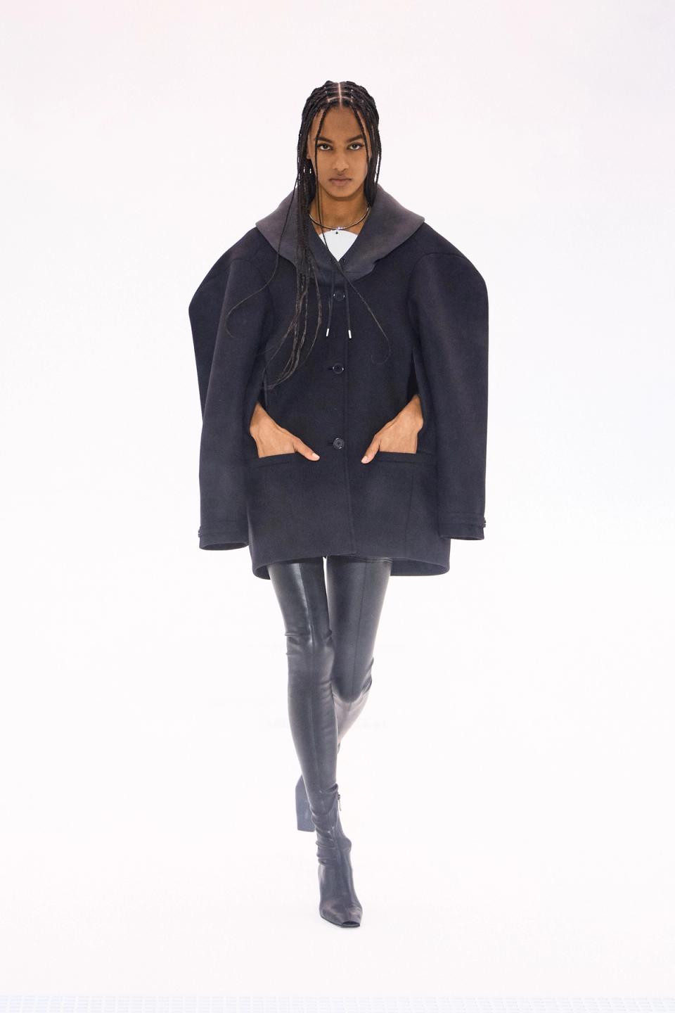 Elegant black shiny leather ensemble with modern style, showcased on a runway for Courrèges.