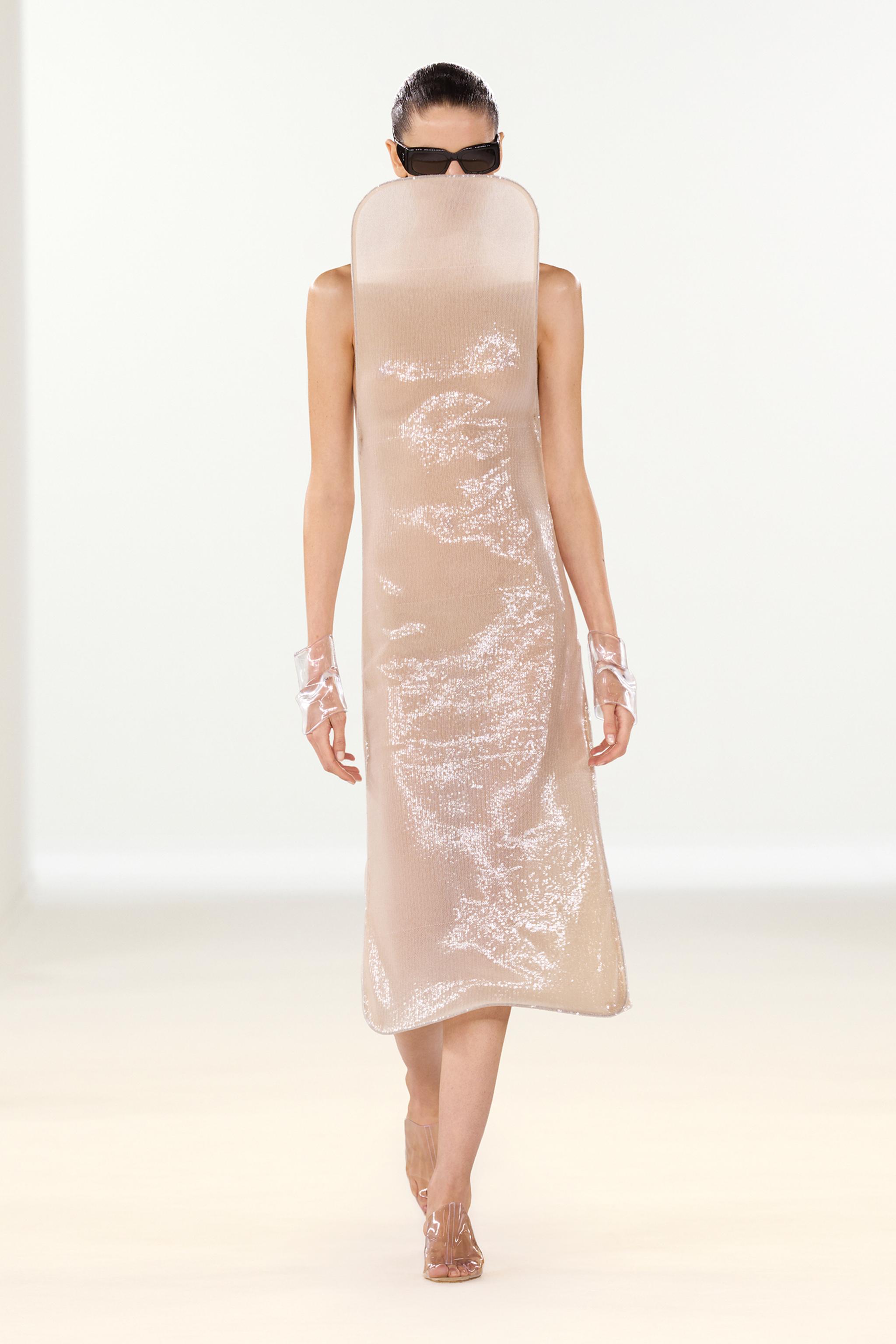 Elegant model wearing designer fashion by Courrèges, runway-ready look with shiny, neutral-toned dress.
