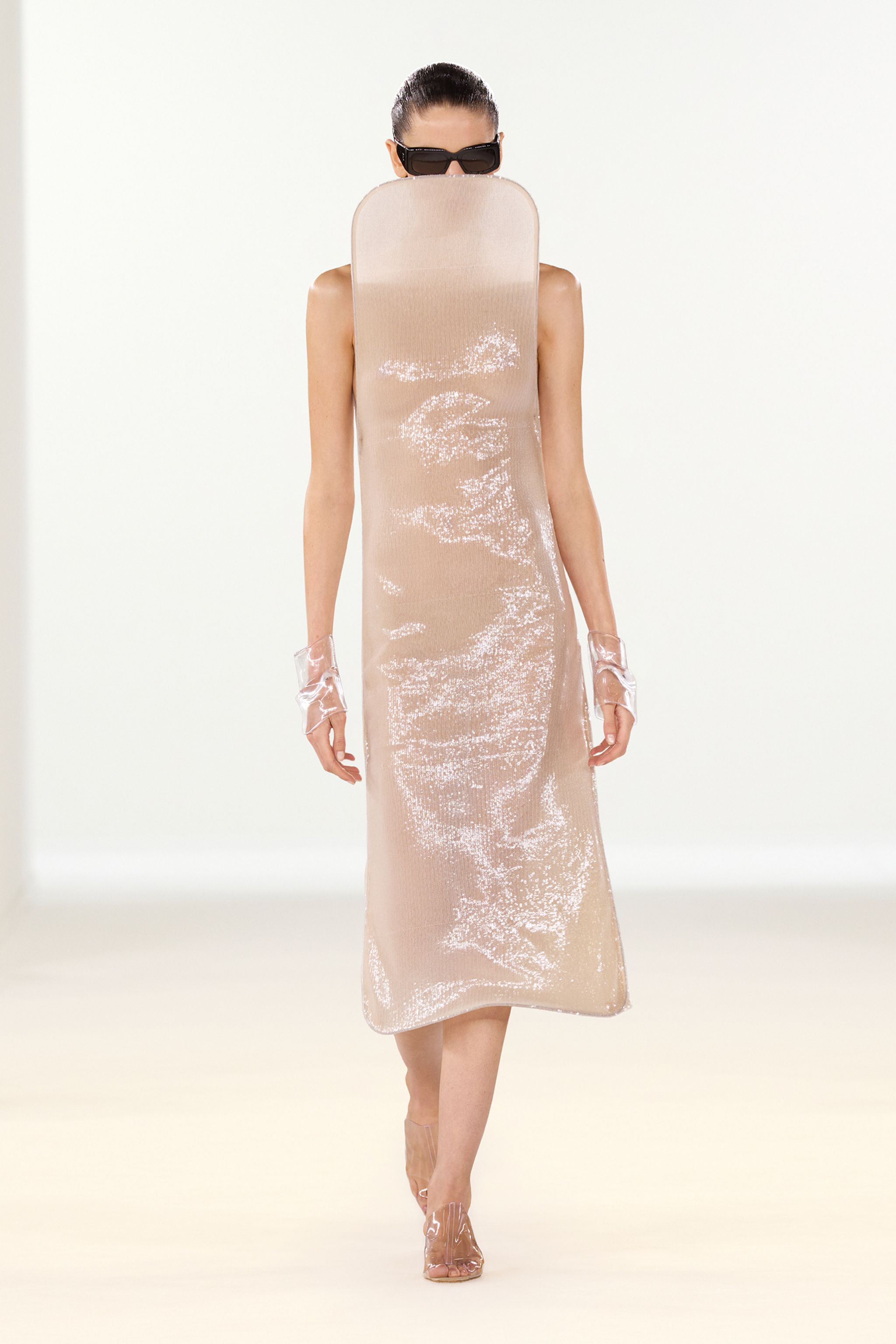 Elegant, minimalist beige dress with shiny accents for Courrèges fashion showcased on runway.