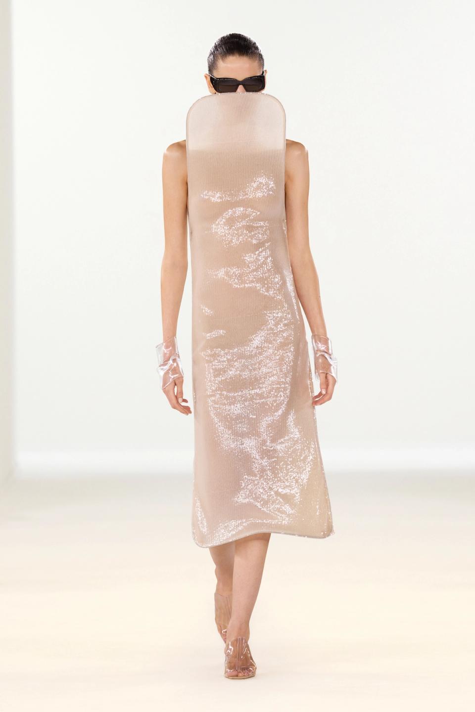 Elegant, minimalist beige dress with shiny accents for Courrèges fashion showcased on runway.