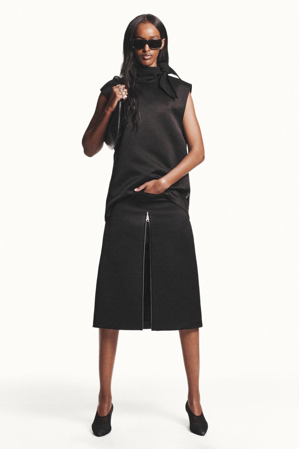 Elegant black Courrèges fashion ensemble featuring a sleeveless top, skirt with front zipper, and stylish accessories.