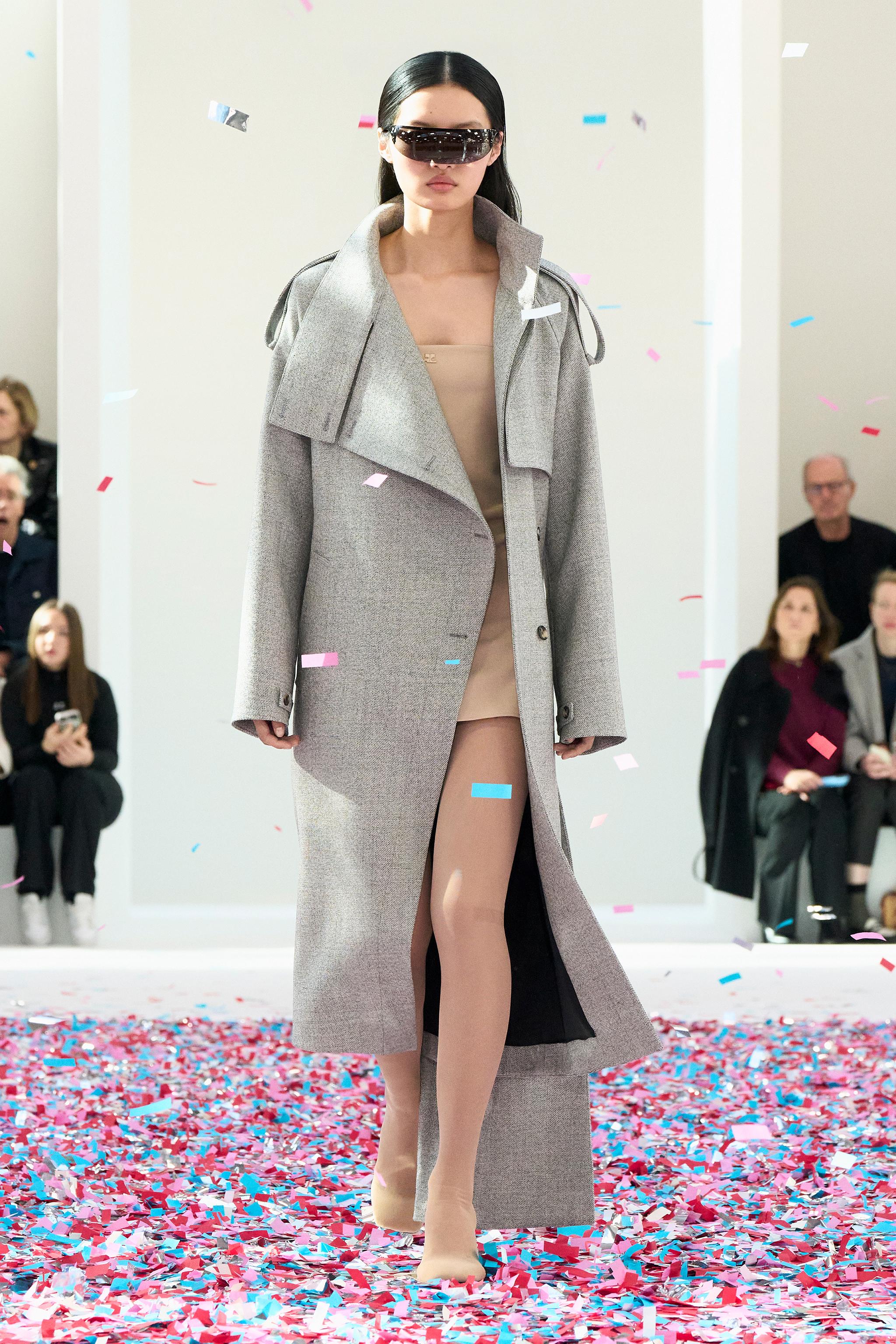 Elegant runway model in a gray coat and beige dress, showcasing Courrèges fashion for an ecommerce site.