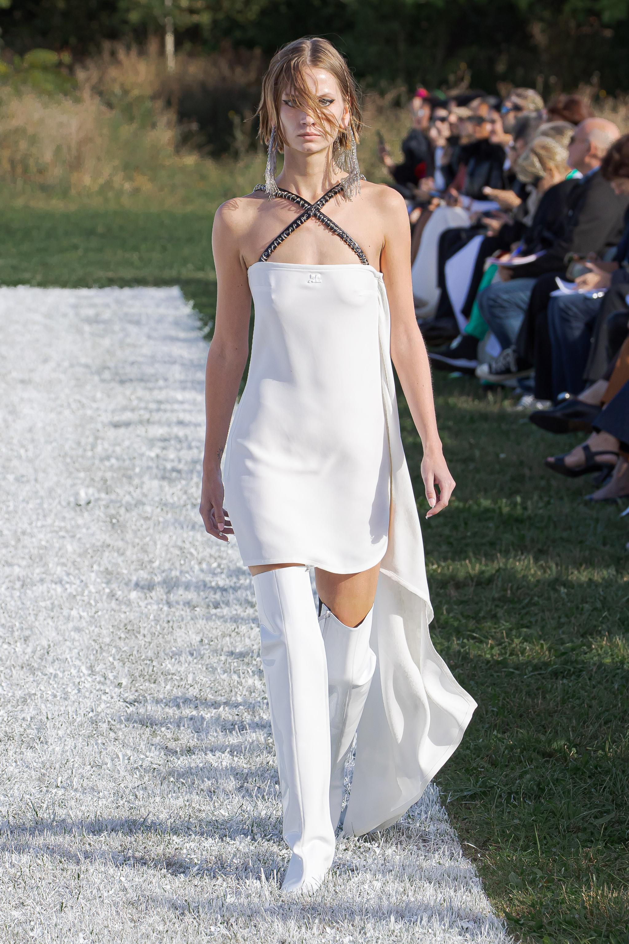 Elegant white fashion dress with knee-high accessories, showcased on a runway for Courrèges.