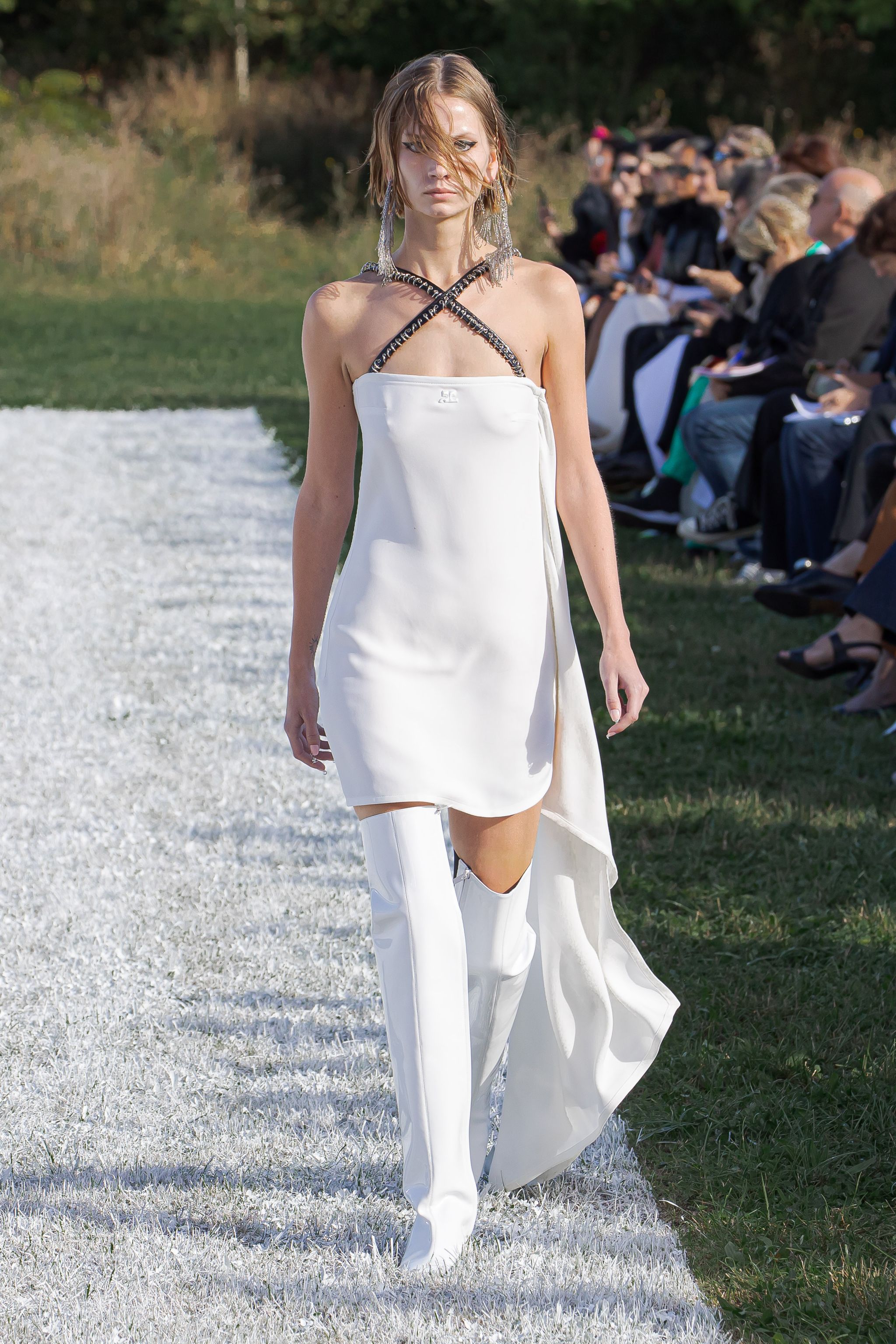 Elegant white fashion dress with knee-high accessories, showcased on a runway for Courrèges.