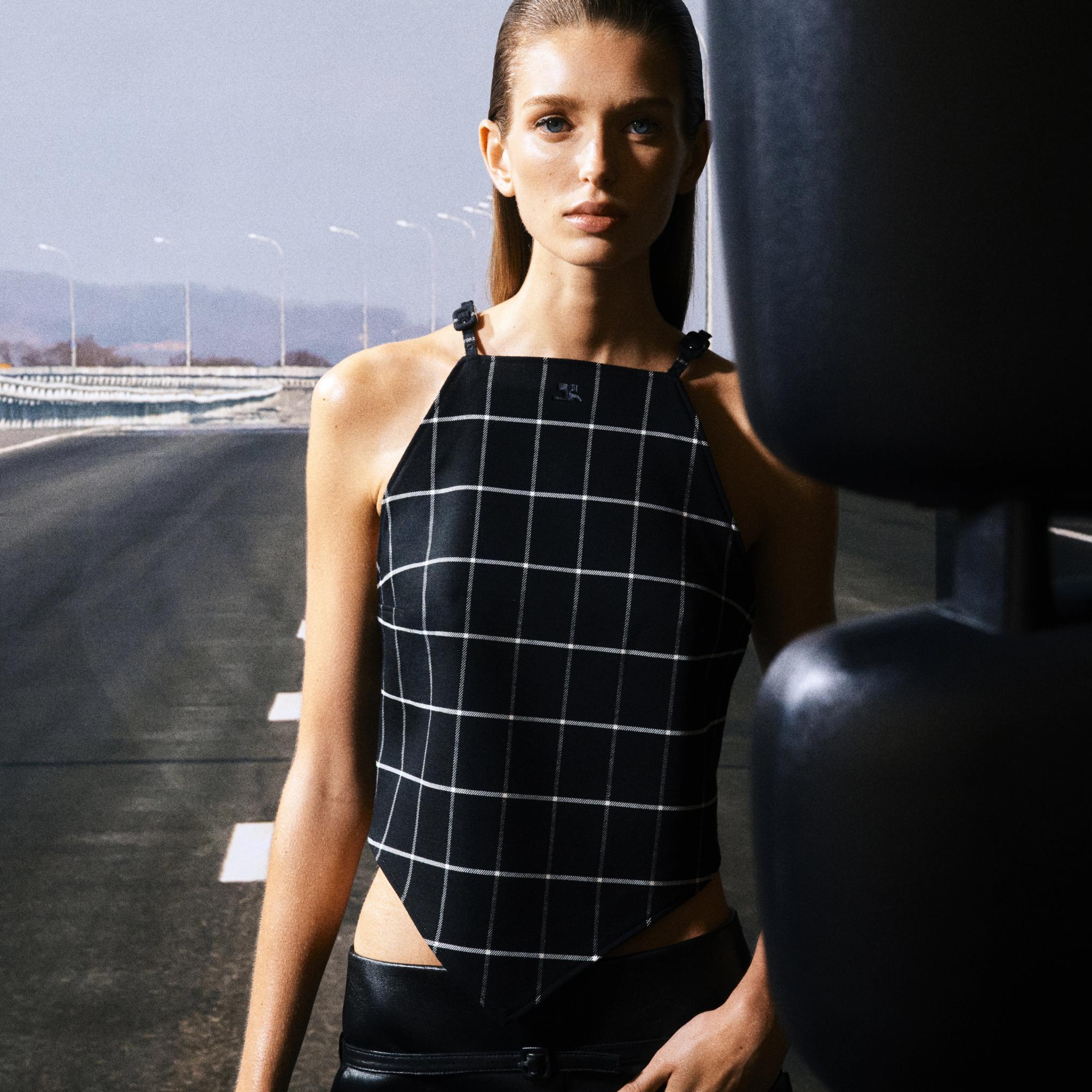 Haut à carreaux noirs élégant de Courrèges sur un modèle avec un fond urbain moderne.