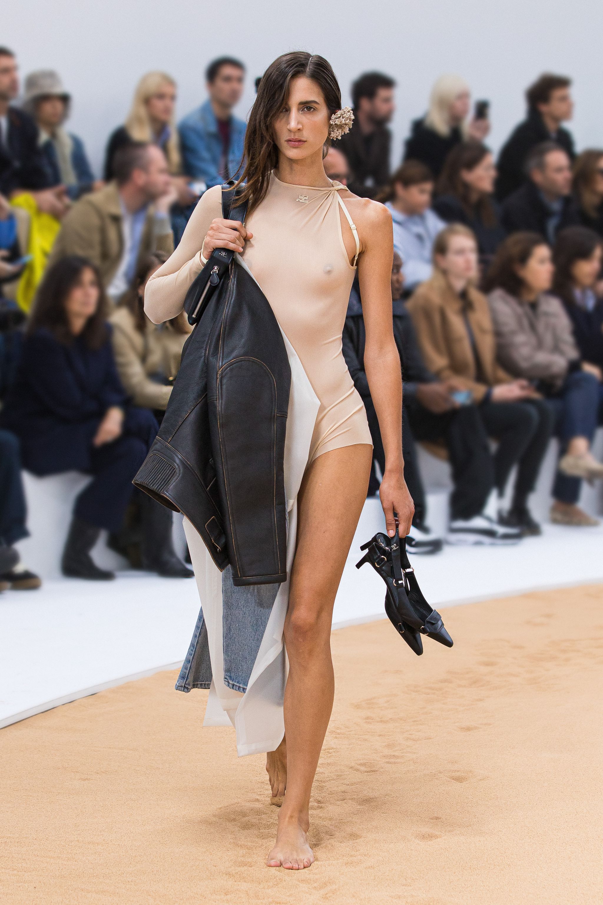Elegant fashion runway look by Courrèges featuring a beige dress, leather jacket, and accessories.