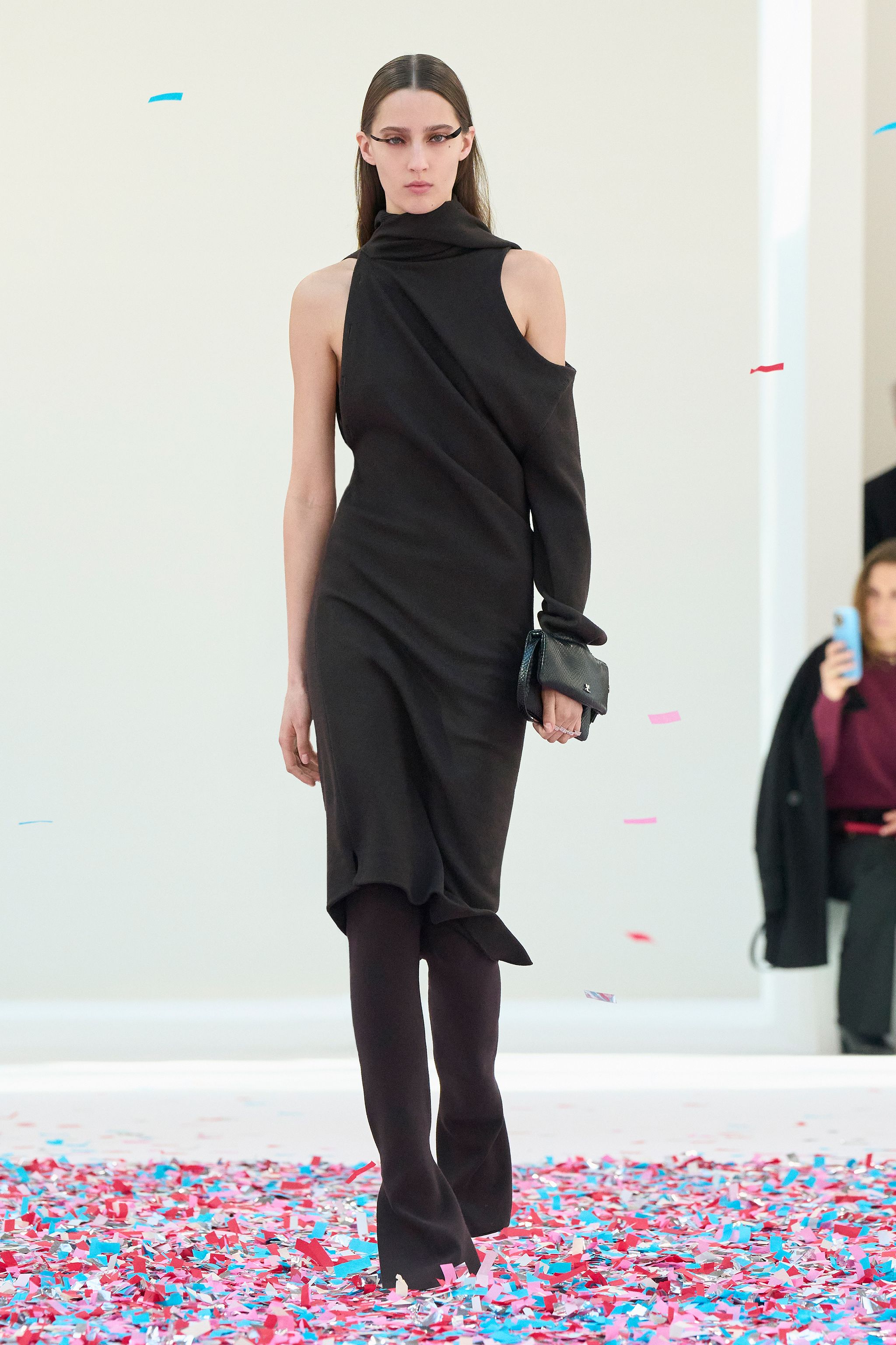 Elegant black asymmetric dress with a high neckline, showcased on a model on the runway for Courrèges.