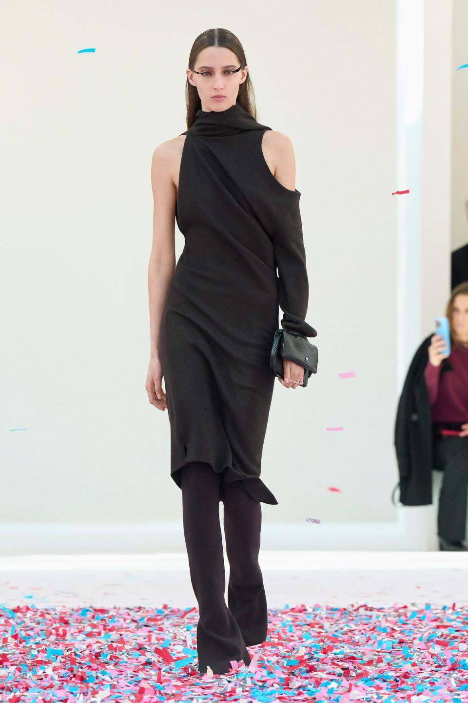 Elegant black asymmetric dress with a high neckline, showcased on a model on the runway for Courrèges.