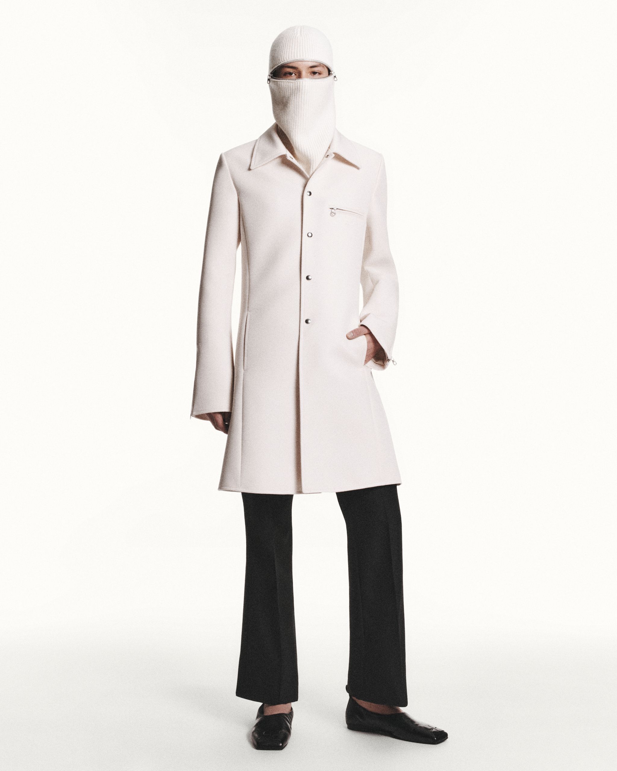 Elegant white coat with zipper details, styled with black pants, on an ecommerce site for Courrèges.