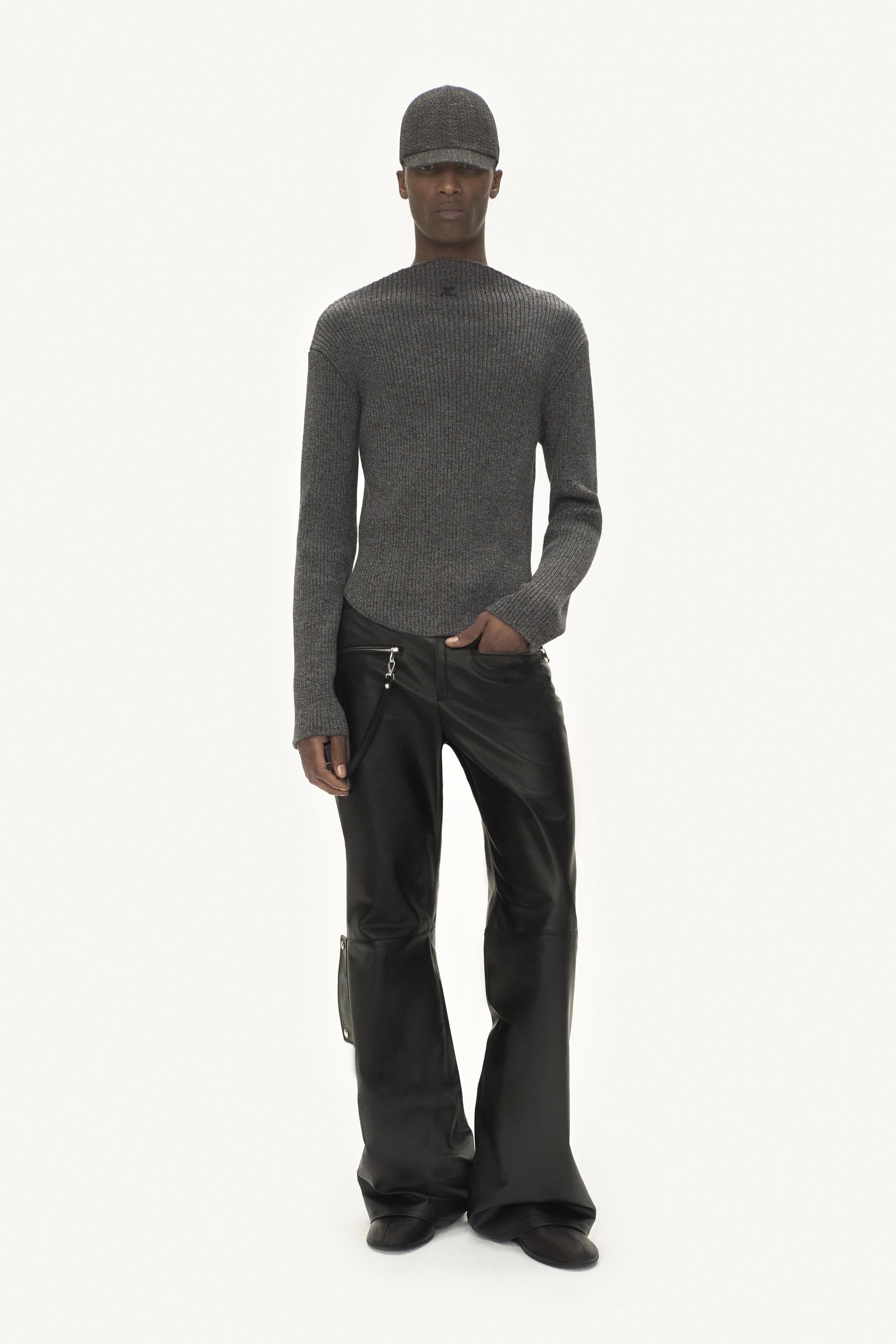 Pull gris élégant et pantalon en cuir noir porté par un mannequin pour la mode Courrèges.