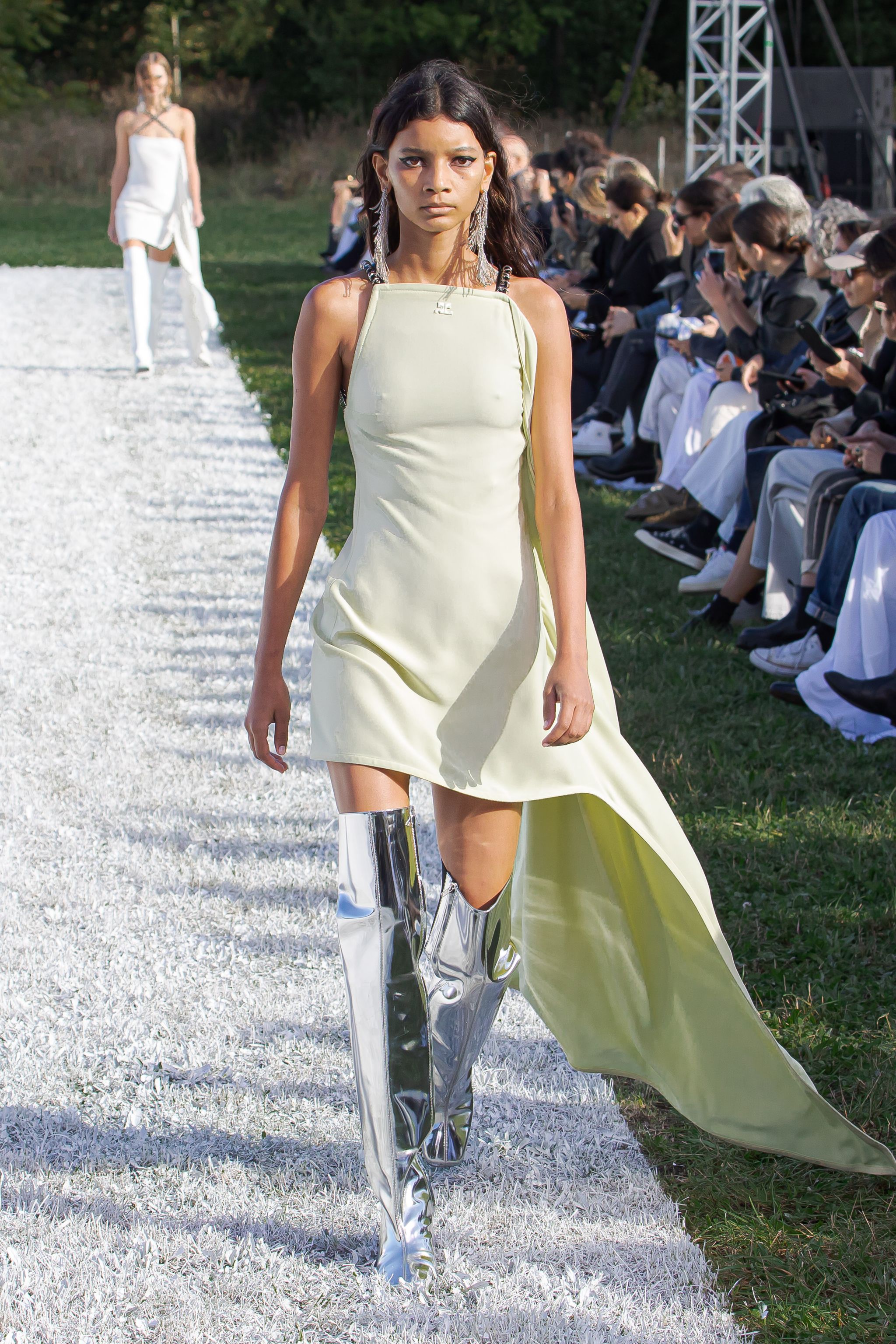 Elegant fashion model walking on runway showcasing Courrèges modern dress with metallic boots.